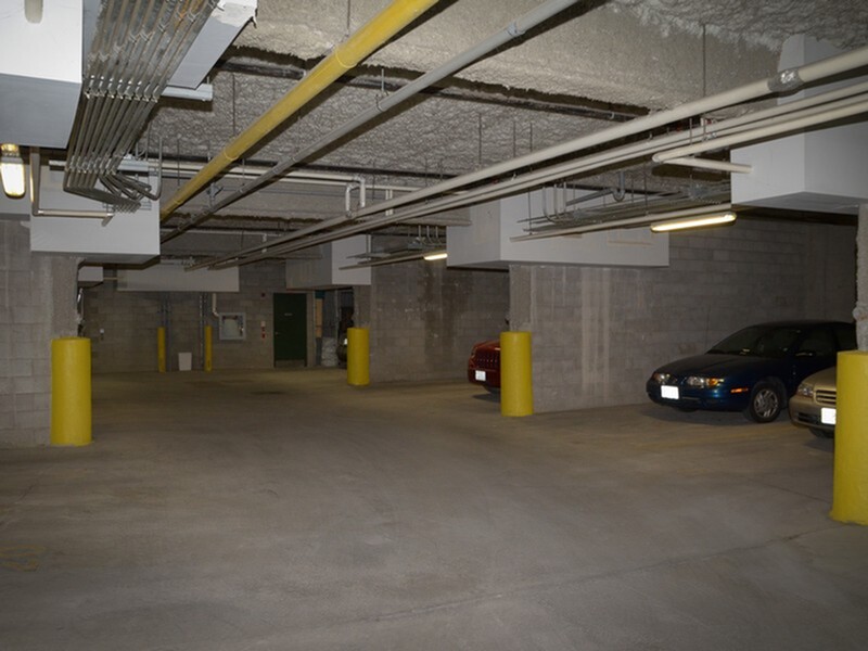 Secure and well-lit underground parking garage with multiple spaces and safety pillars, offering convenient access for residents.
