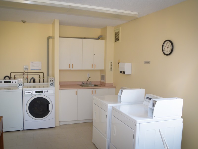 Bright and functional laundry room featuring modern washers, dryers, and ample storage space.