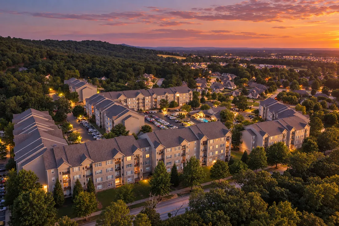 Aerial view at sunset of Mountain Ranch Apartments and the surrounding wooded hills in Fayetteville, AR