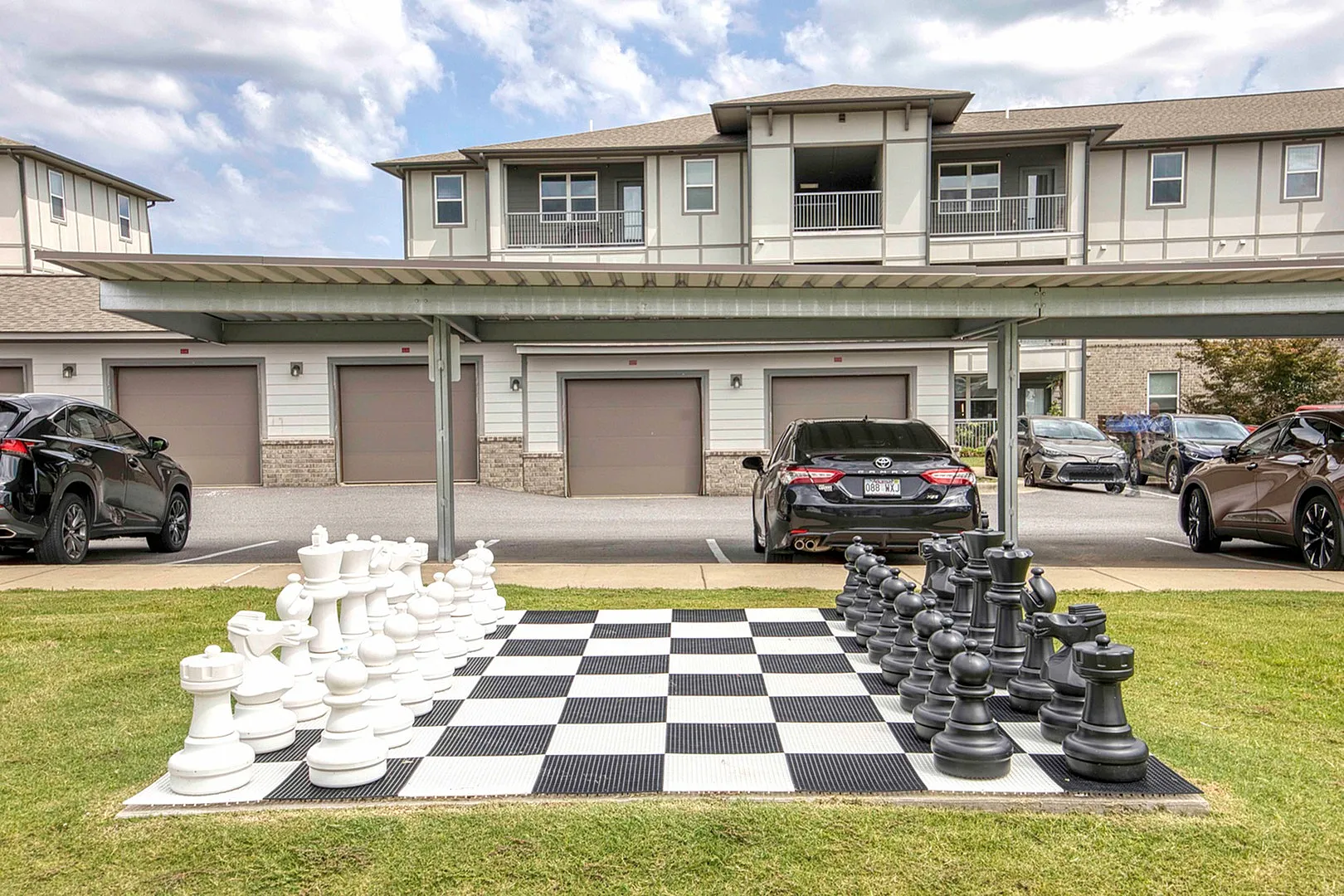 Contemporary apartment complex with an eye-catching giant outdoor chess set, offering unique recreational space and covered parking.