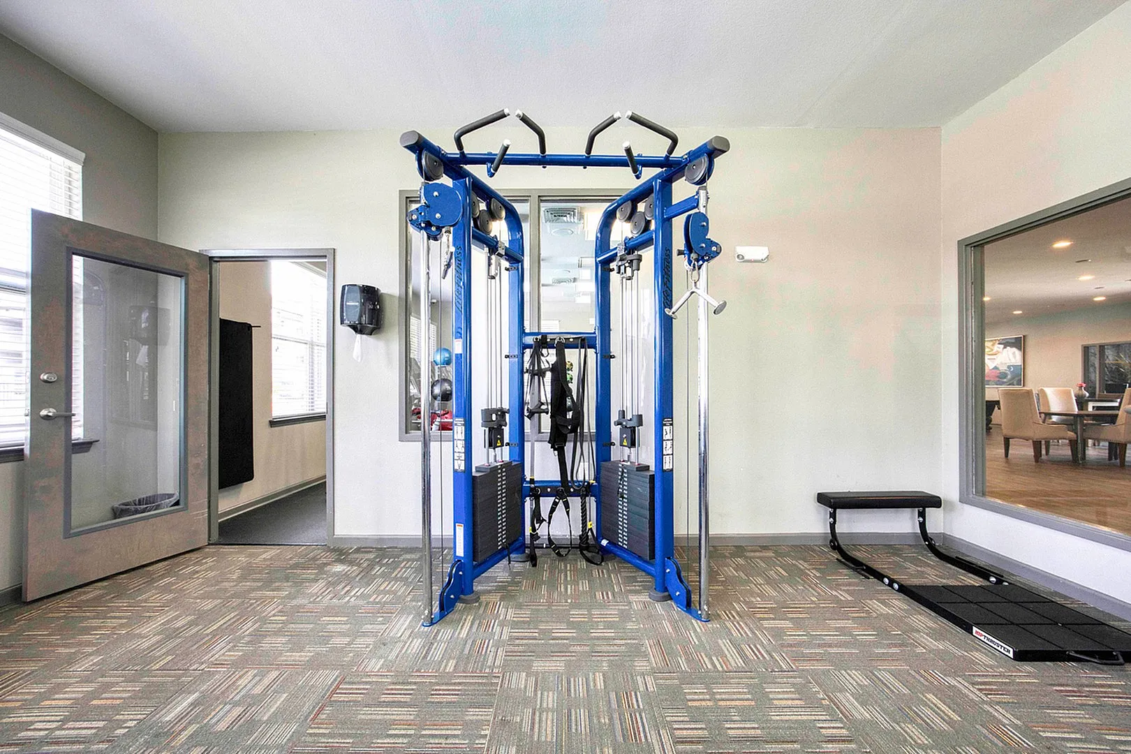 Modern apartment gym featuring state-of-the-art multi-functional exercise equipment under bright natural lighting.