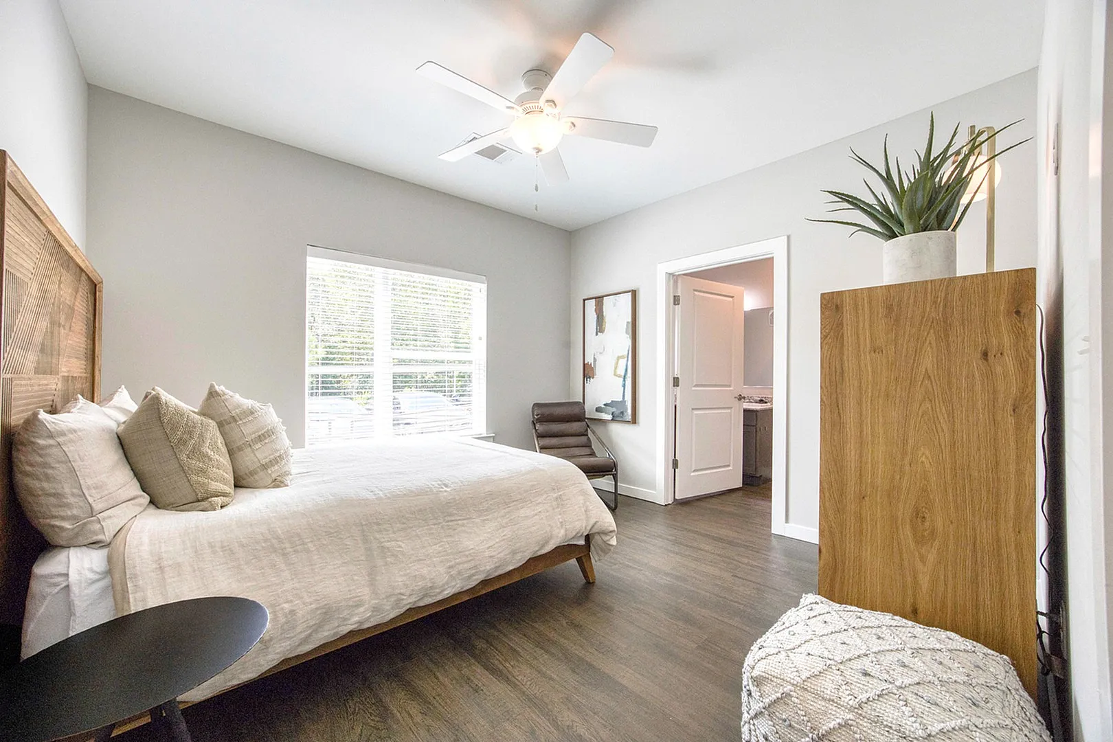 Bright and inviting bedroom with modern decor, featuring a comfortable bed, stylish wooden furniture, and a large window for natural light.