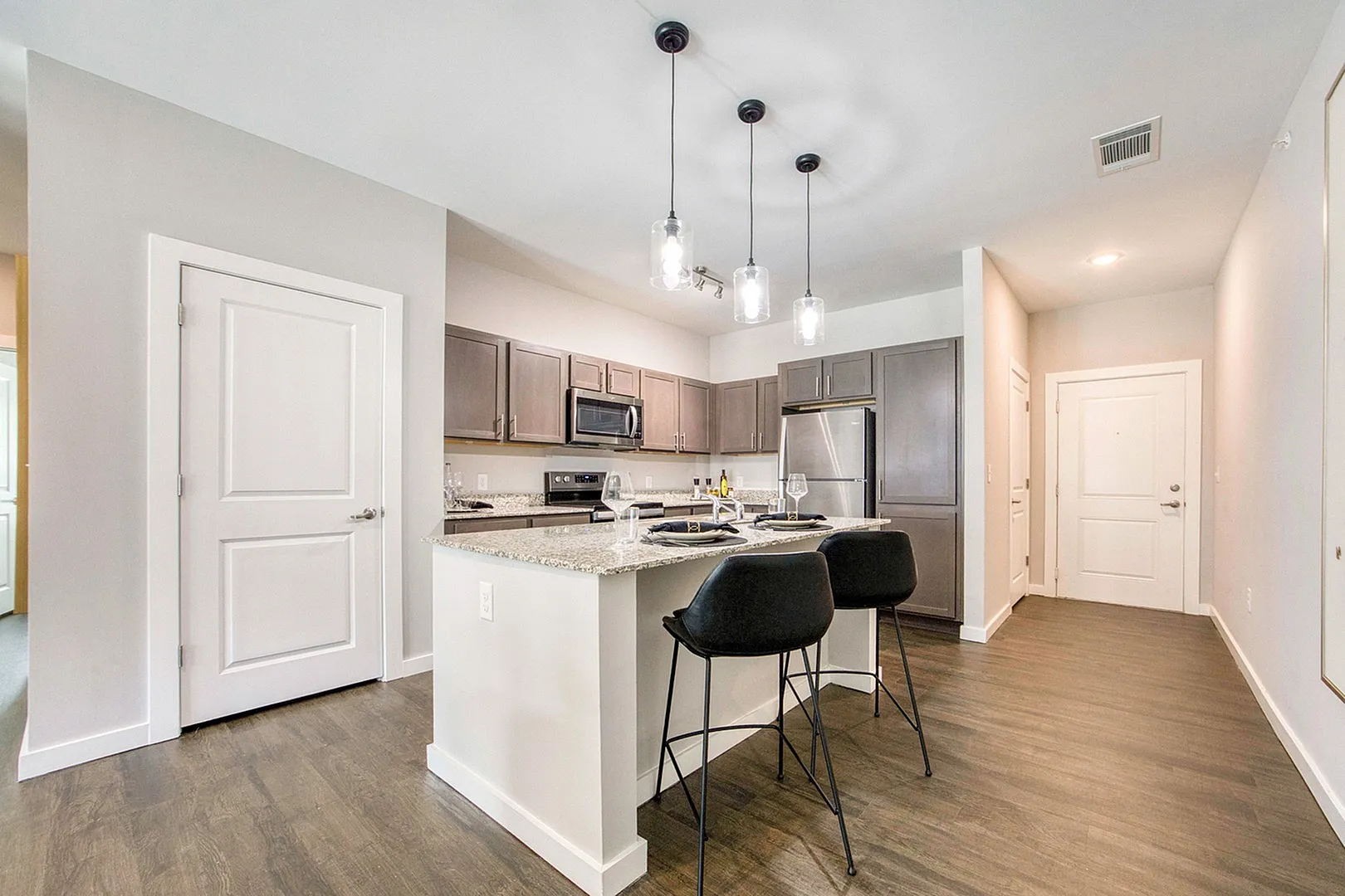 Elegant modern kitchen showcasing a granite-topped island, sleek bar stools, and stylish pendant lighting for an inviting dining experience.