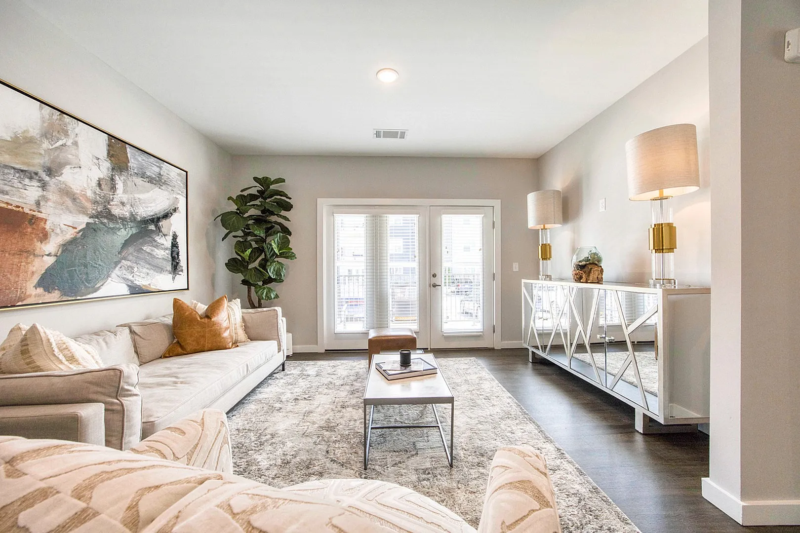 Bright and elegant living room with modern decor, featuring a plush sofa, chic artwork, and large windows allowing ample natural light.