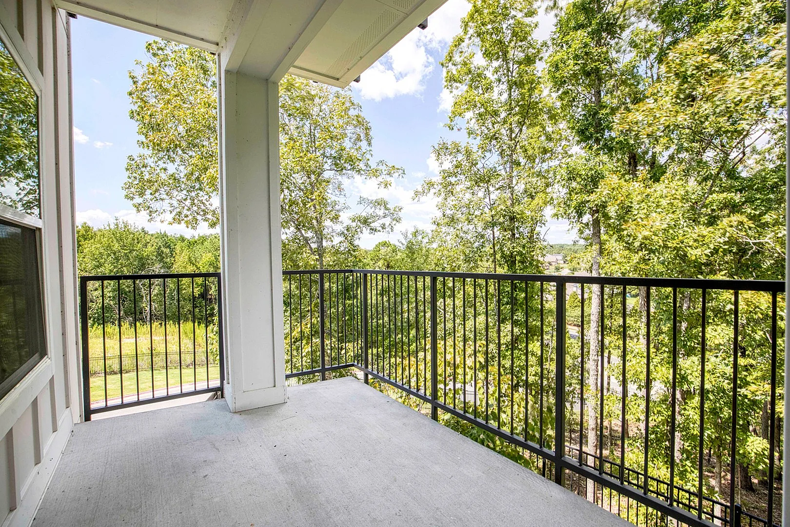 Charming balcony offering a serene view of lush green trees, perfect for relaxation and enjoying nature.