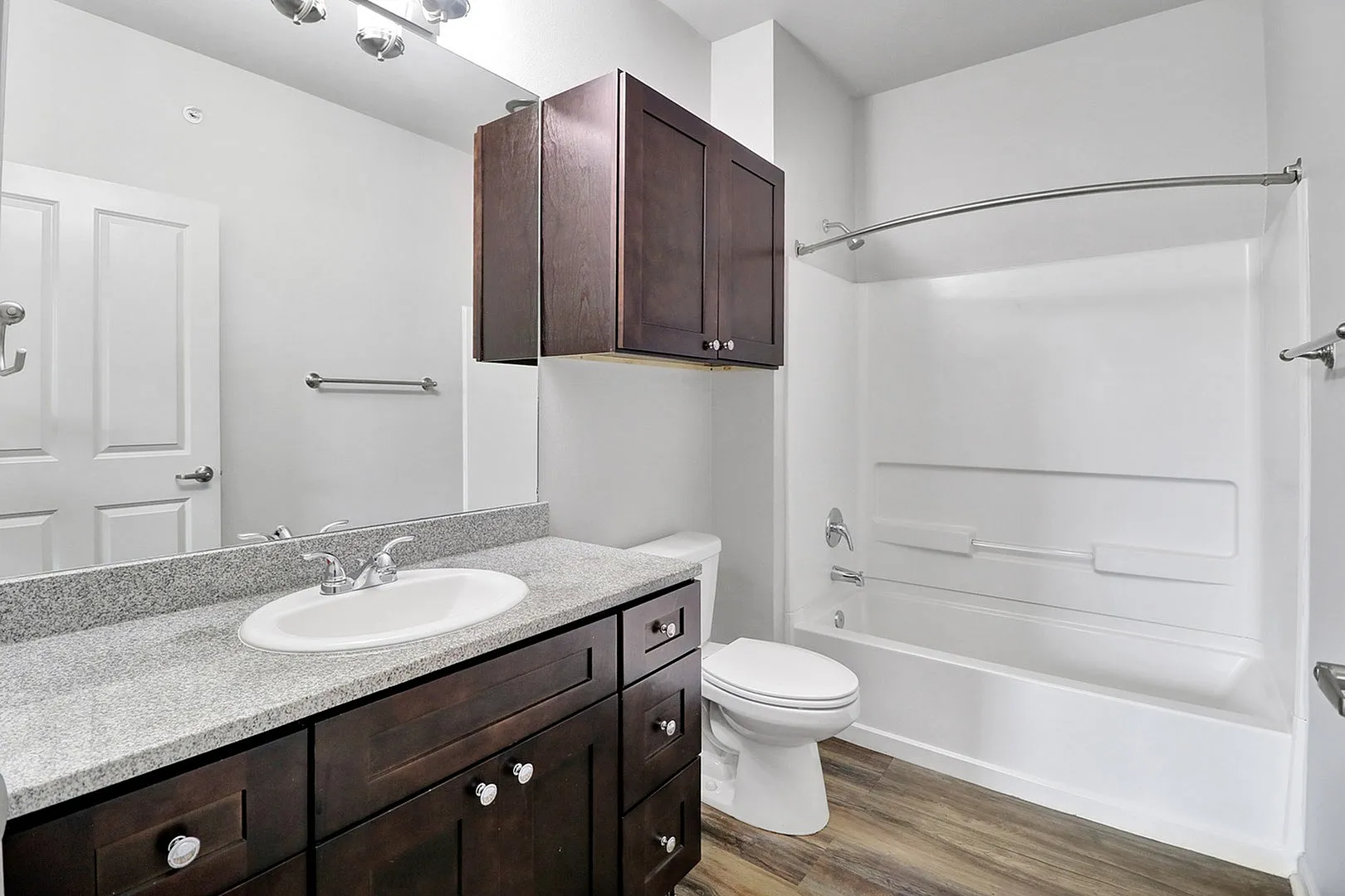 Elegant bathroom with modern fixtures, dark wood cabinetry, granite countertops, and a spacious bathtub.