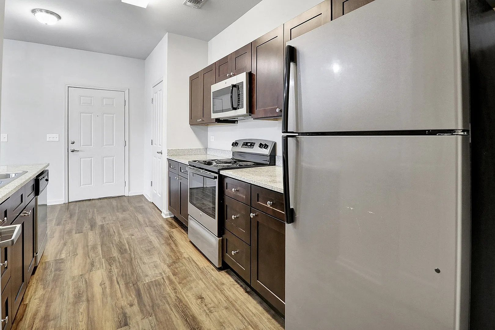 Sleek modern kitchen with stainless steel appliances, dark wood cabinets, and elegant hardwood flooring.