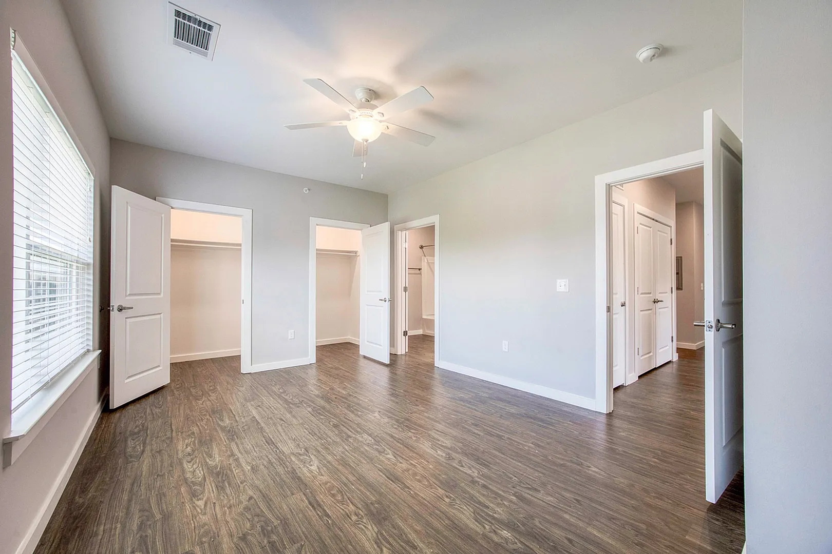 Inviting bedroom with chic wood floors, ample natural light, and spacious walk-in closets.