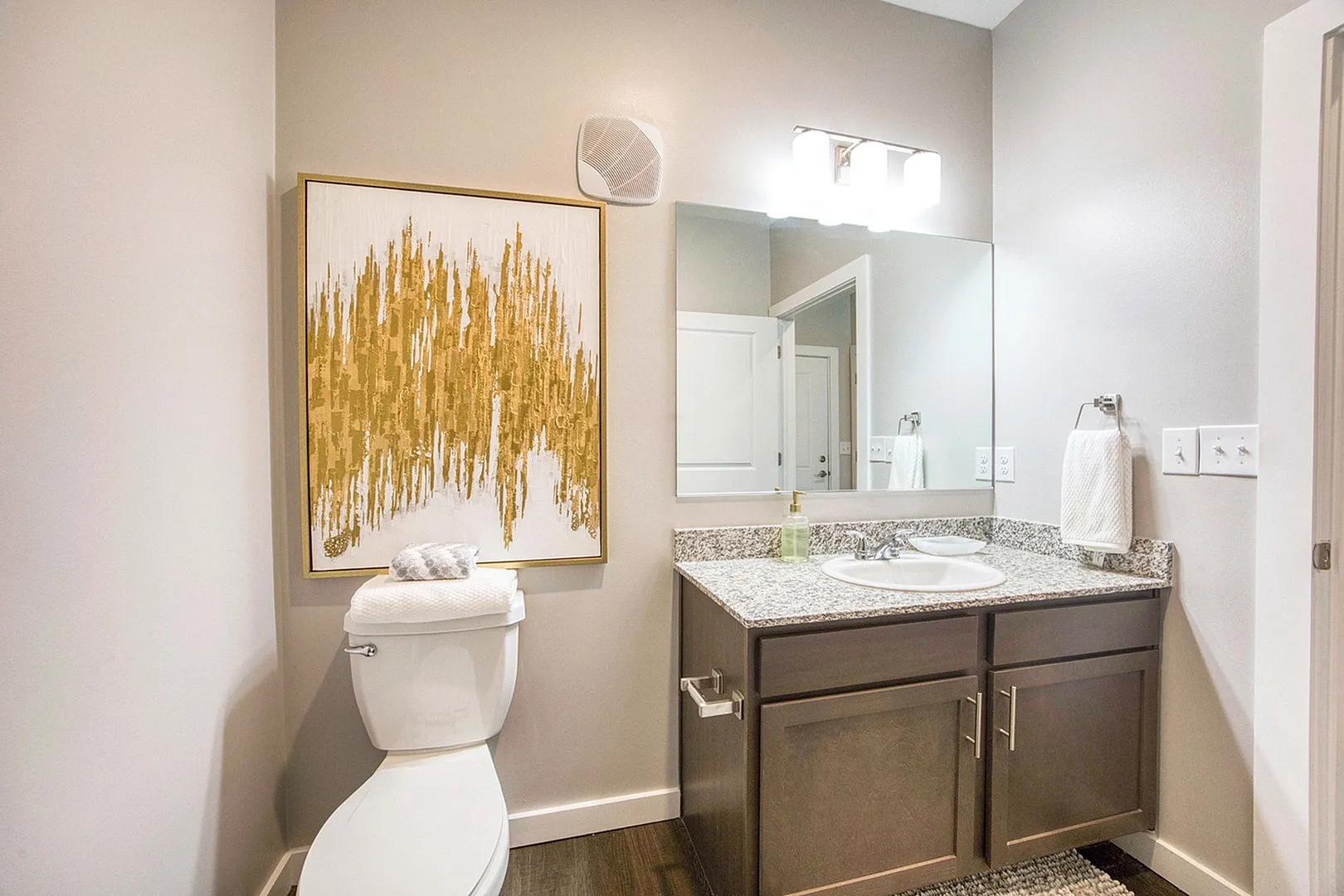 Contemporary bathroom design with elegant granite countertop, chic wall art, and modern lighting.