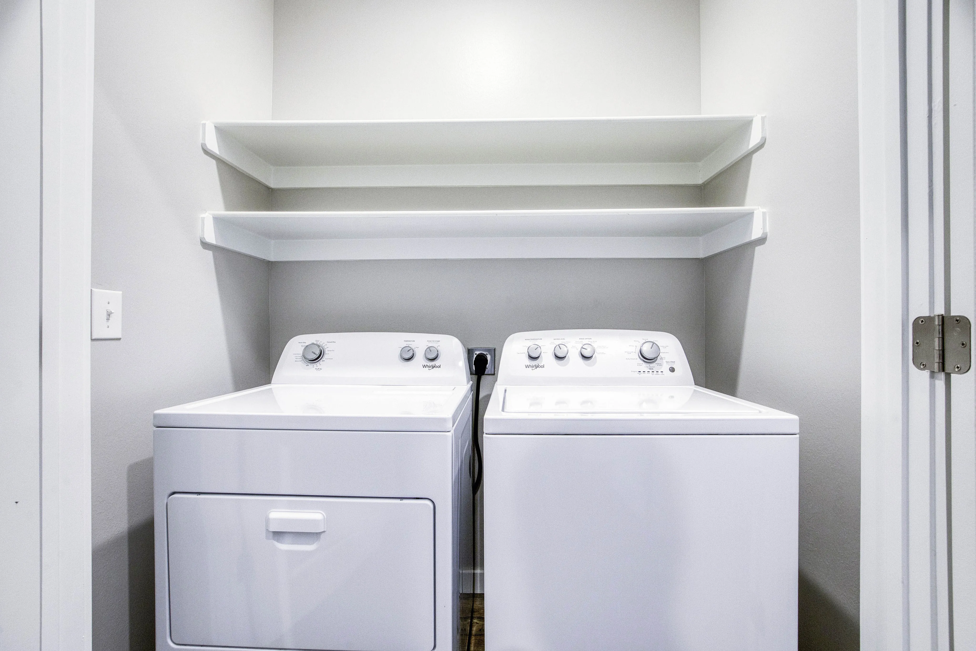 Bright and modern laundry room with high-efficiency washer and dryer, complemented by sleek shelving for storage solutions.