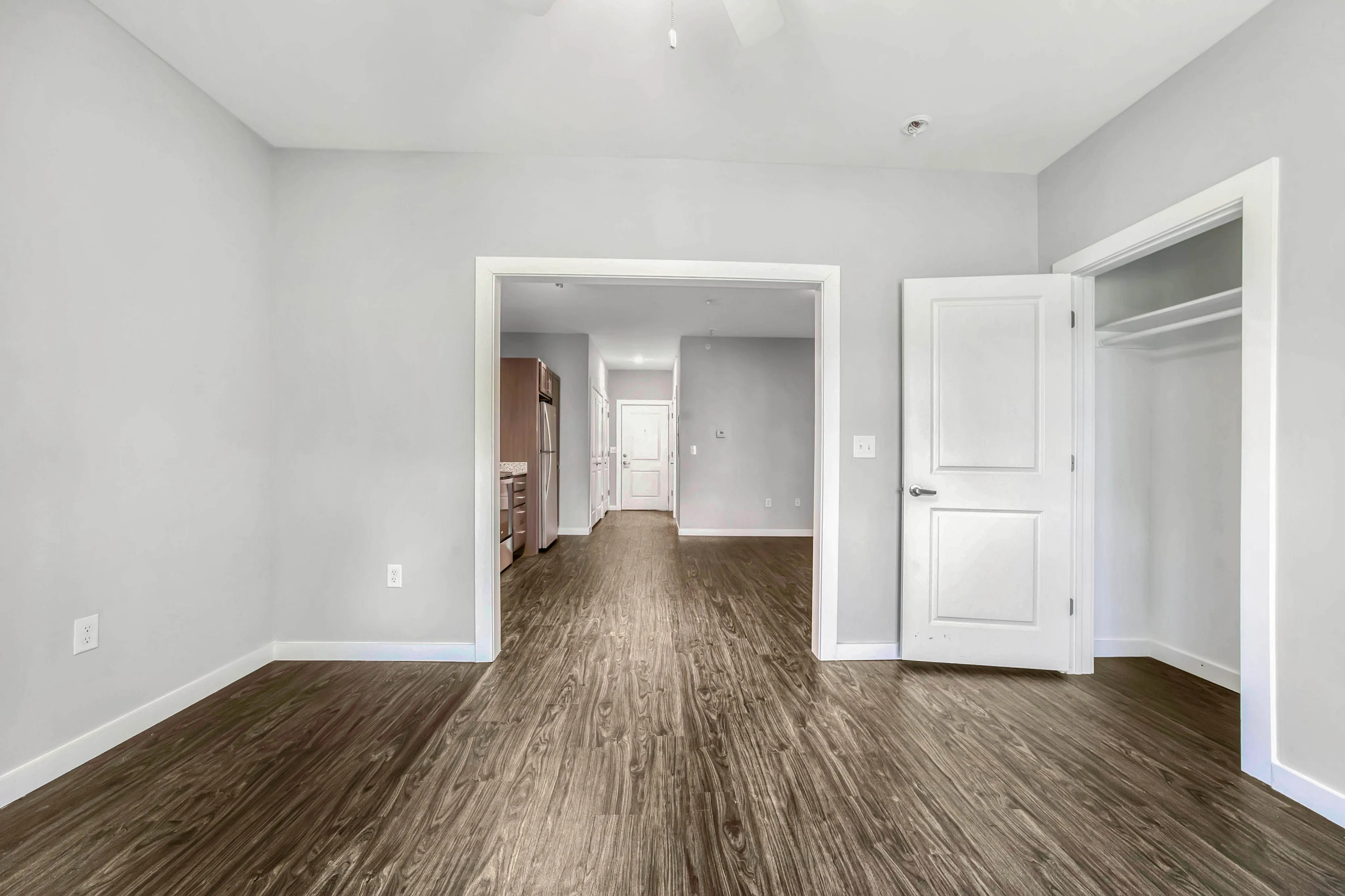 Beautiful open-floor apartment with sleek wooden flooring, spacious closets, and modern kitchen view.