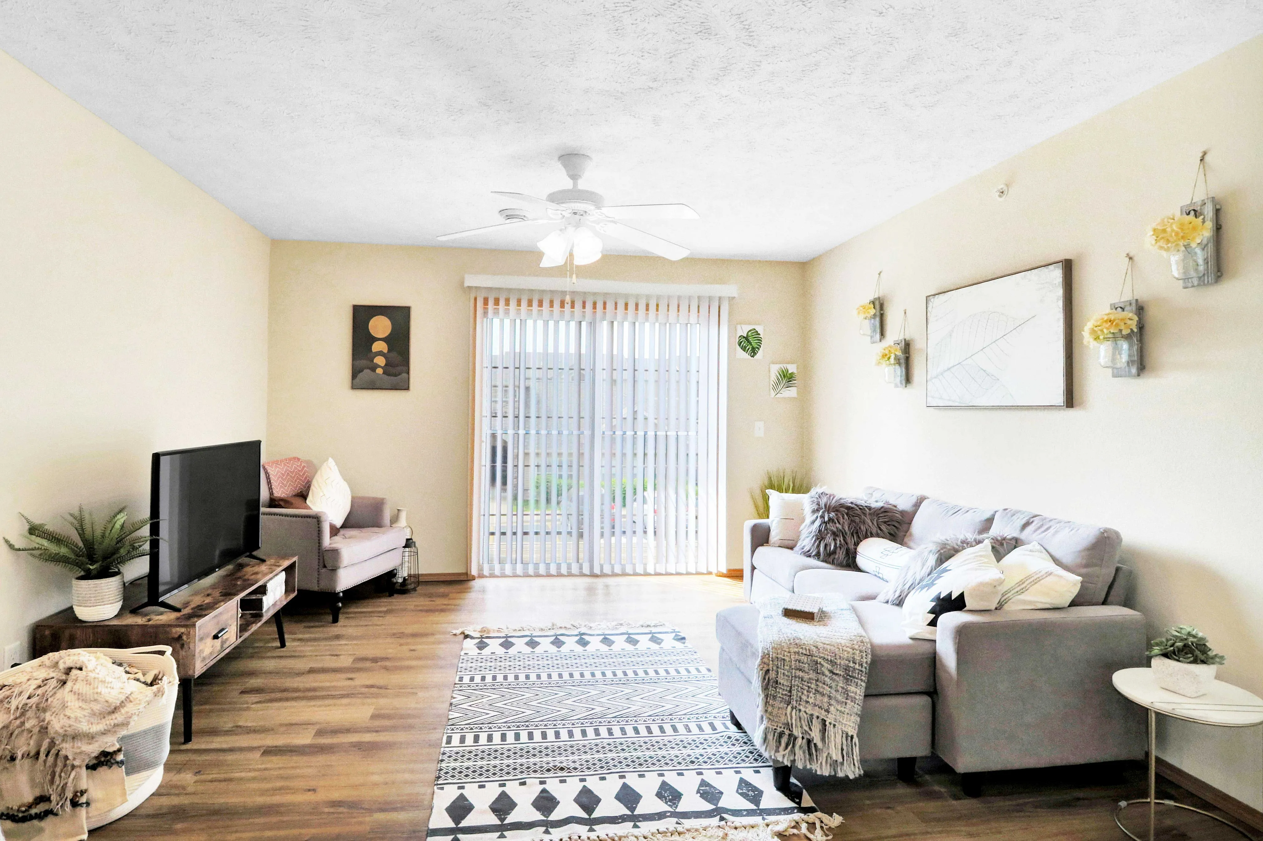 Bright and inviting living room with modern decor, featuring a cozy gray sofa, stylish wall art, and large sliding glass doors that let in natural light.