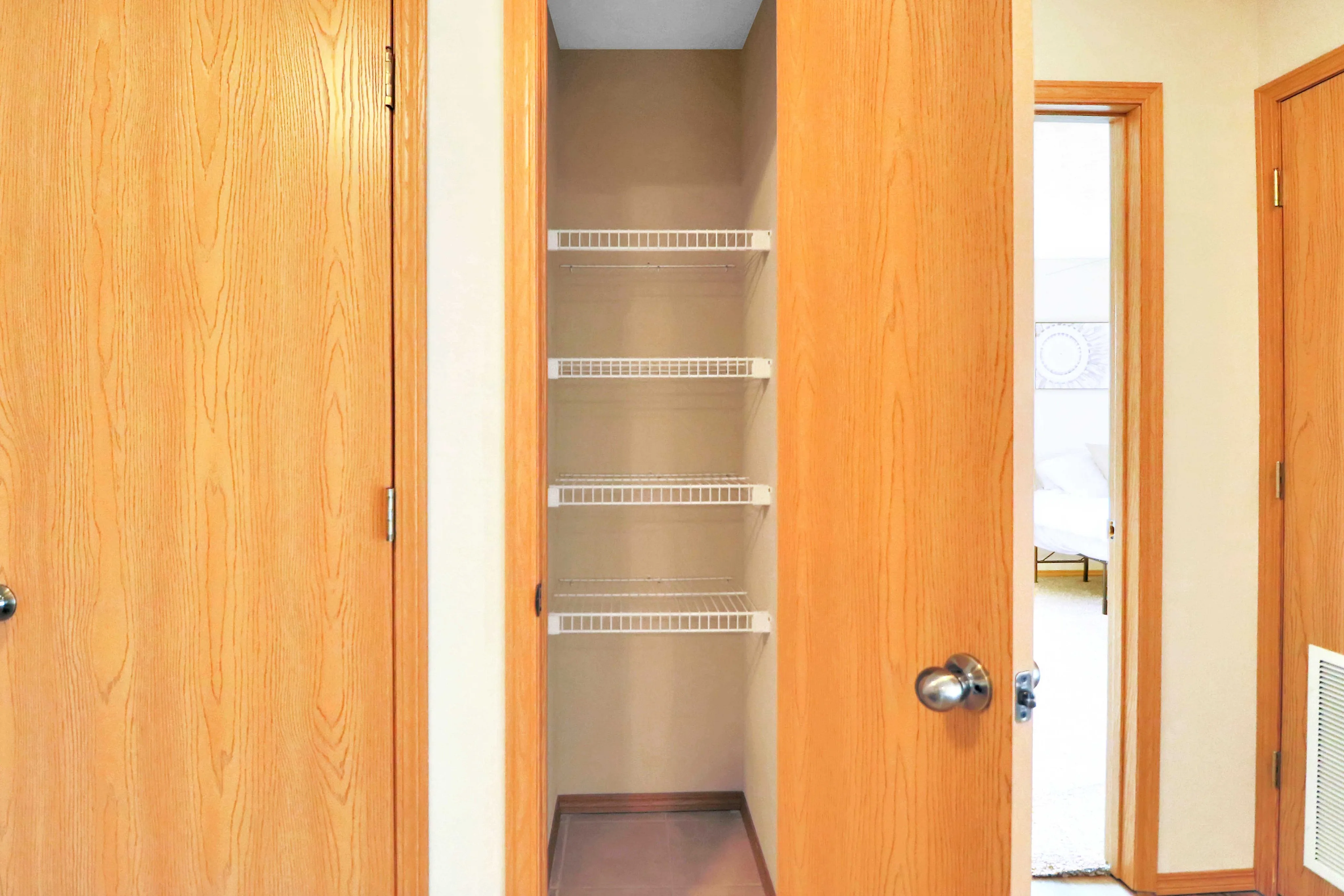 Inviting walk-in closet with wooden doors and ample shelving, ideal for organized storage in a cozy apartment.