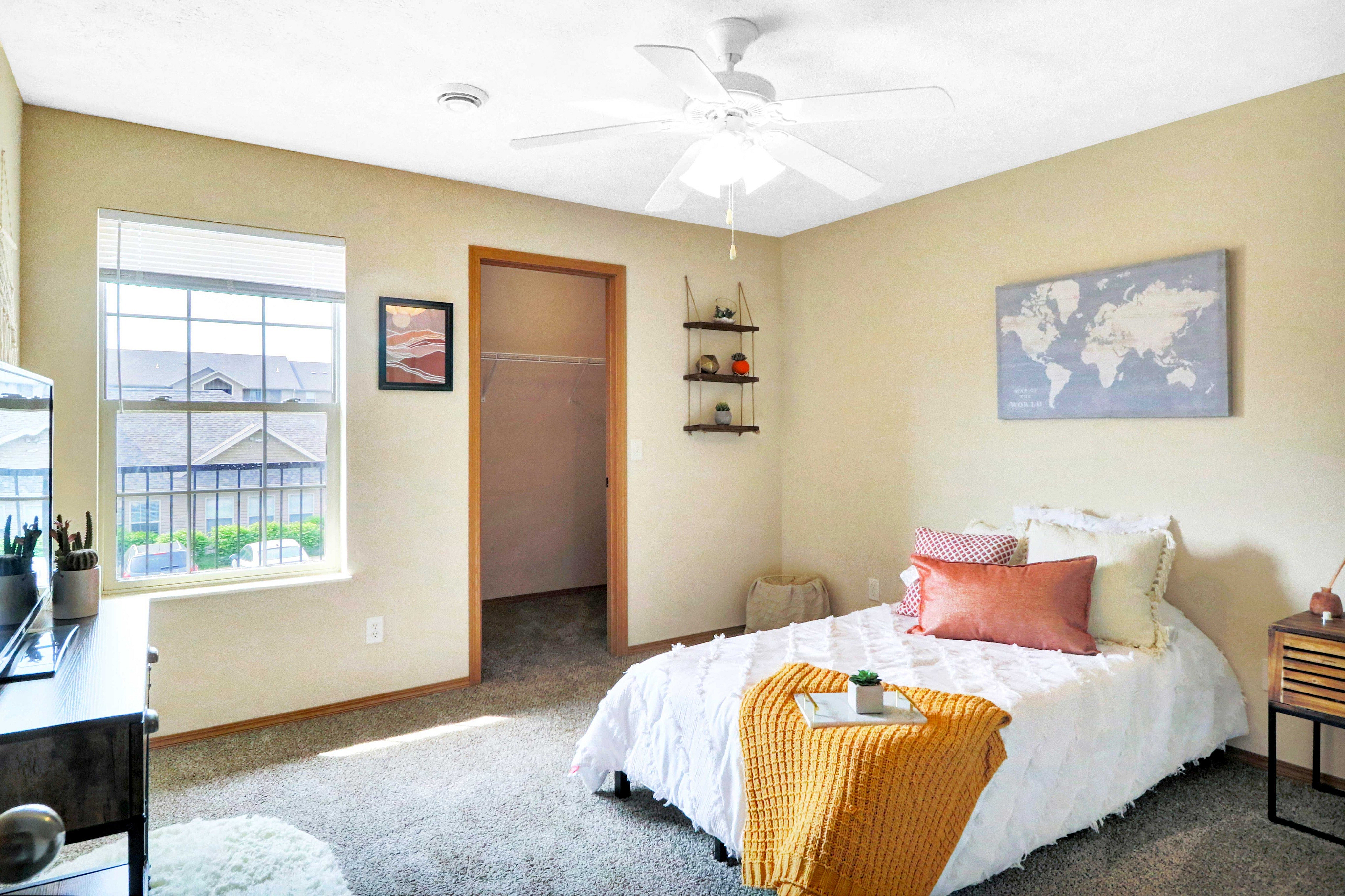 Bright and cozy bedroom with a stylish bed, vibrant pillows, and a spacious walk-in closet. Features a large window with scenic views and elegant decor, perfect for relaxation and comfort.