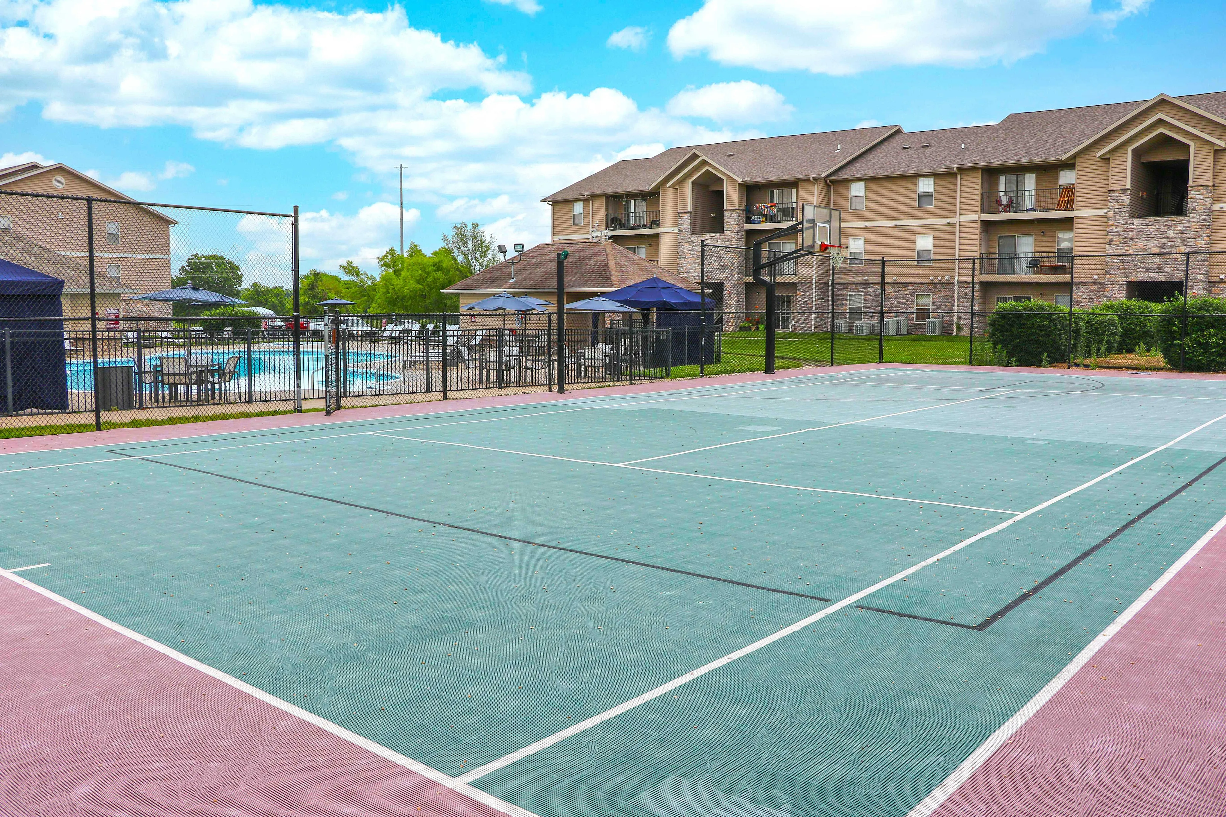 Inviting apartment complex with a vibrant outdoor tennis court and refreshing pool area, perfect for active living and relaxation.