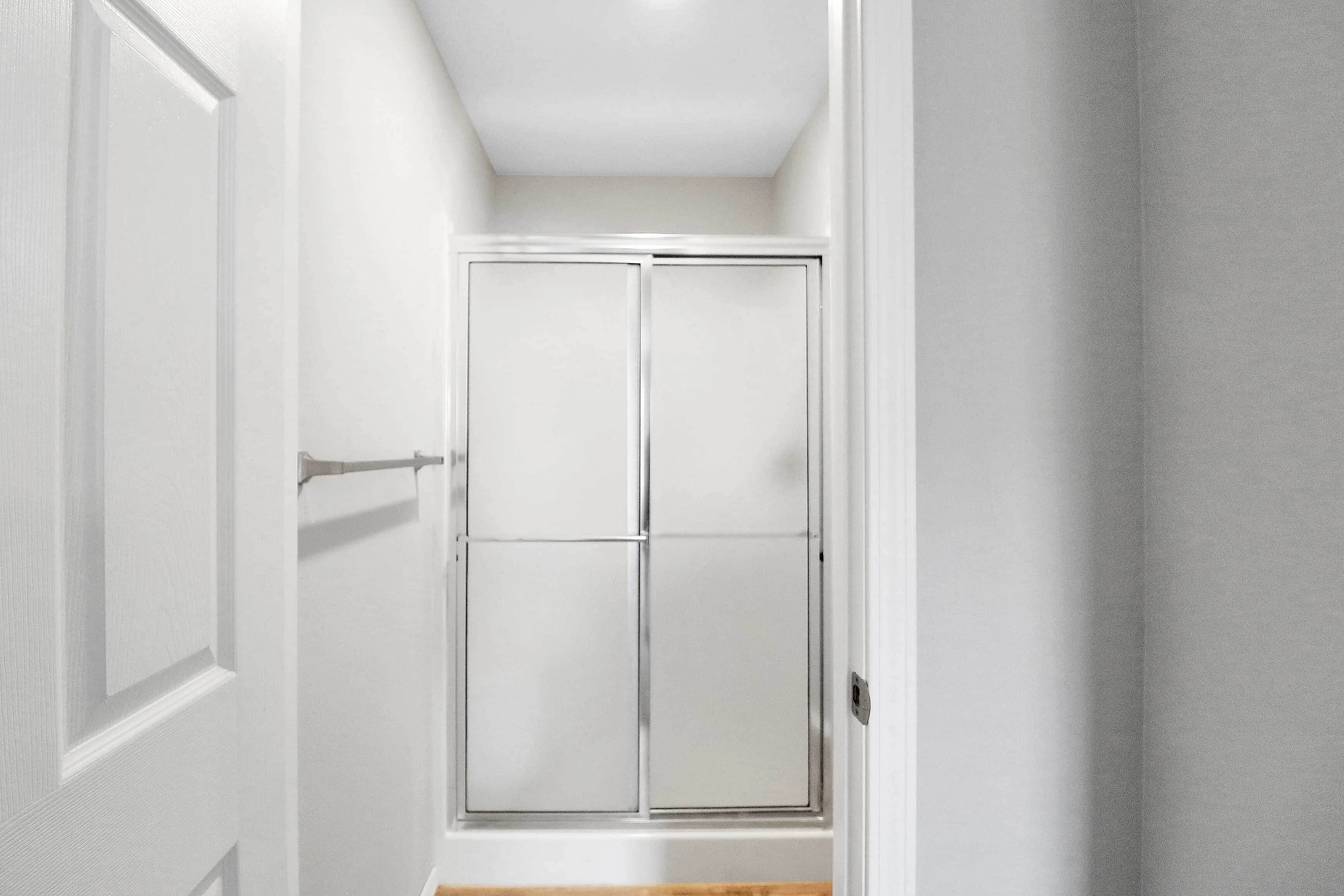 Modern bathroom with sleek frosted glass shower doors and fresh white walls, offering a crisp and clean aesthetic.
