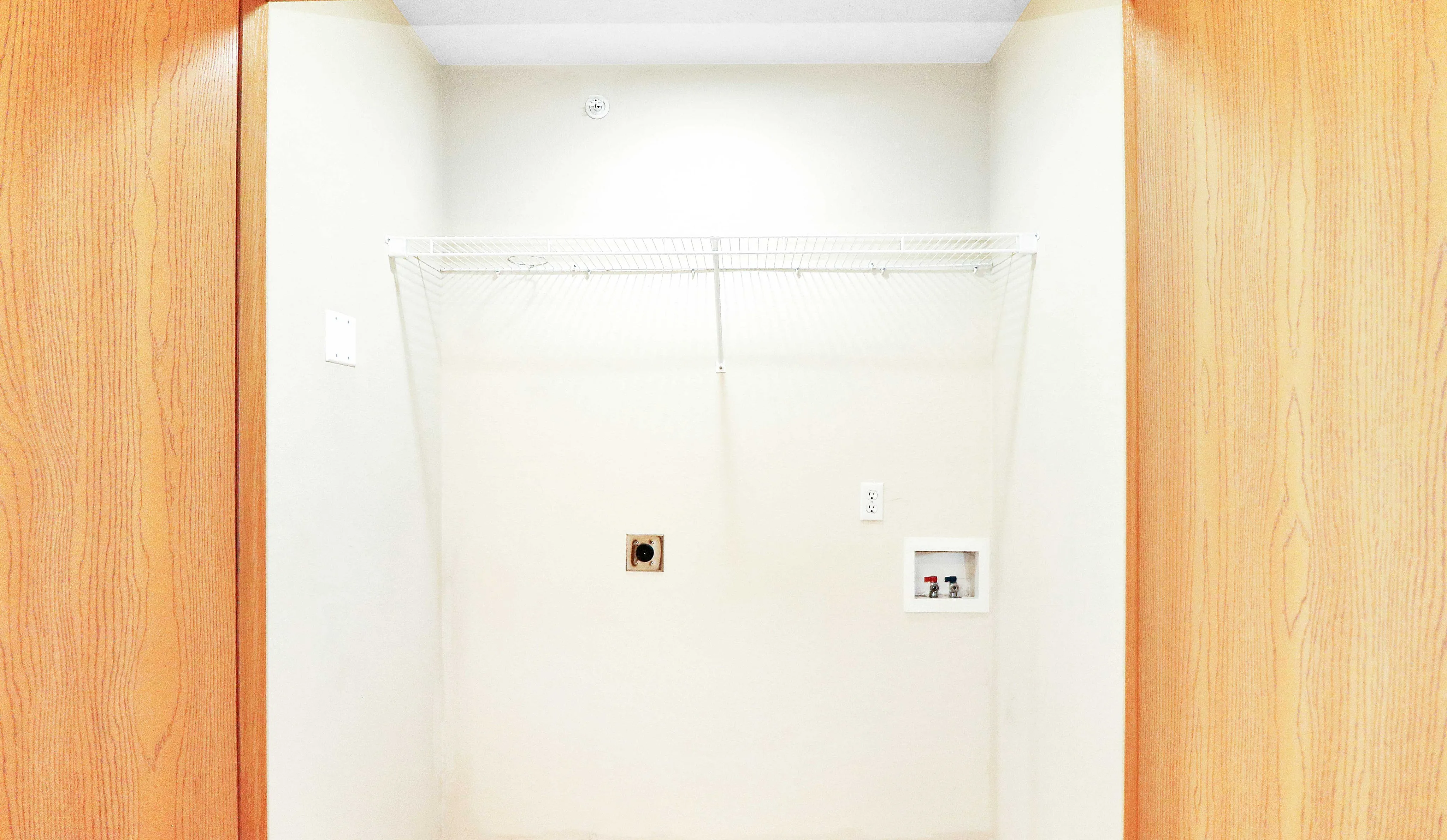 Bright and spacious laundry nook with modern wood accents and utility hookups, perfect for convenient at-home laundry.