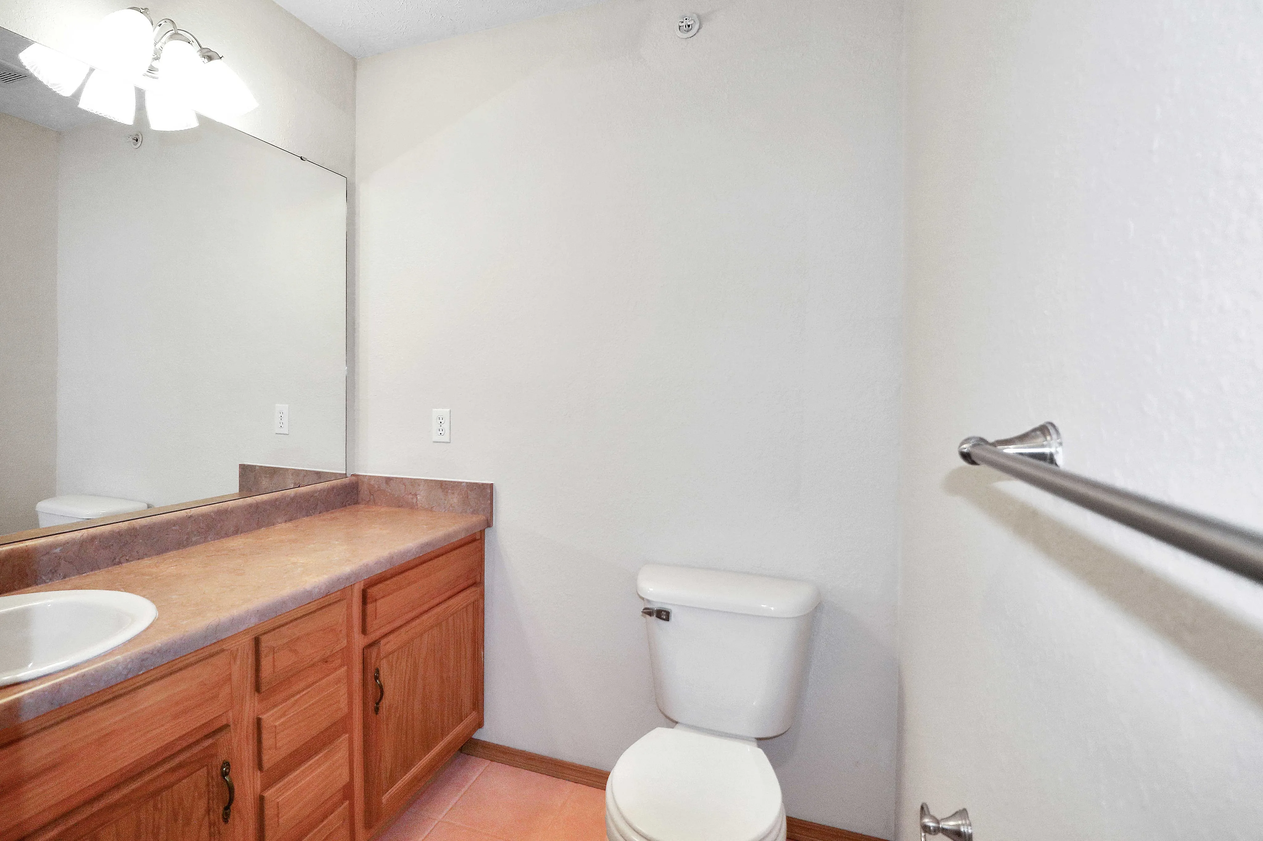 Bright and inviting bathroom featuring a large mirror, elegant wooden vanity, and modern fixtures.