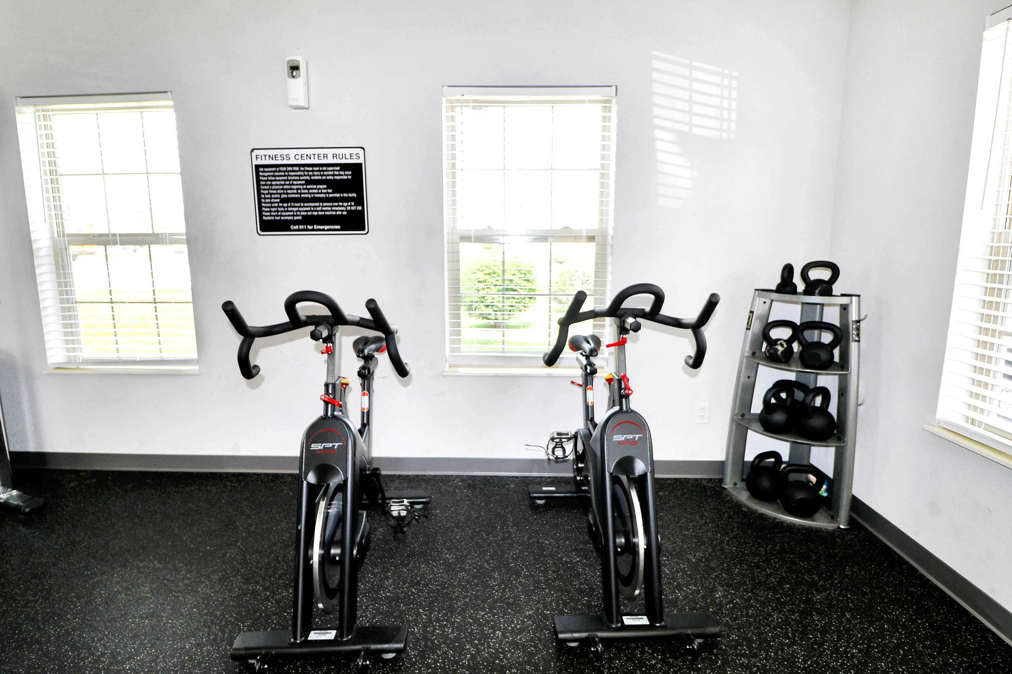 Inviting fitness center with state-of-the-art exercise bikes and kettlebells, bathed in natural light from large windows.