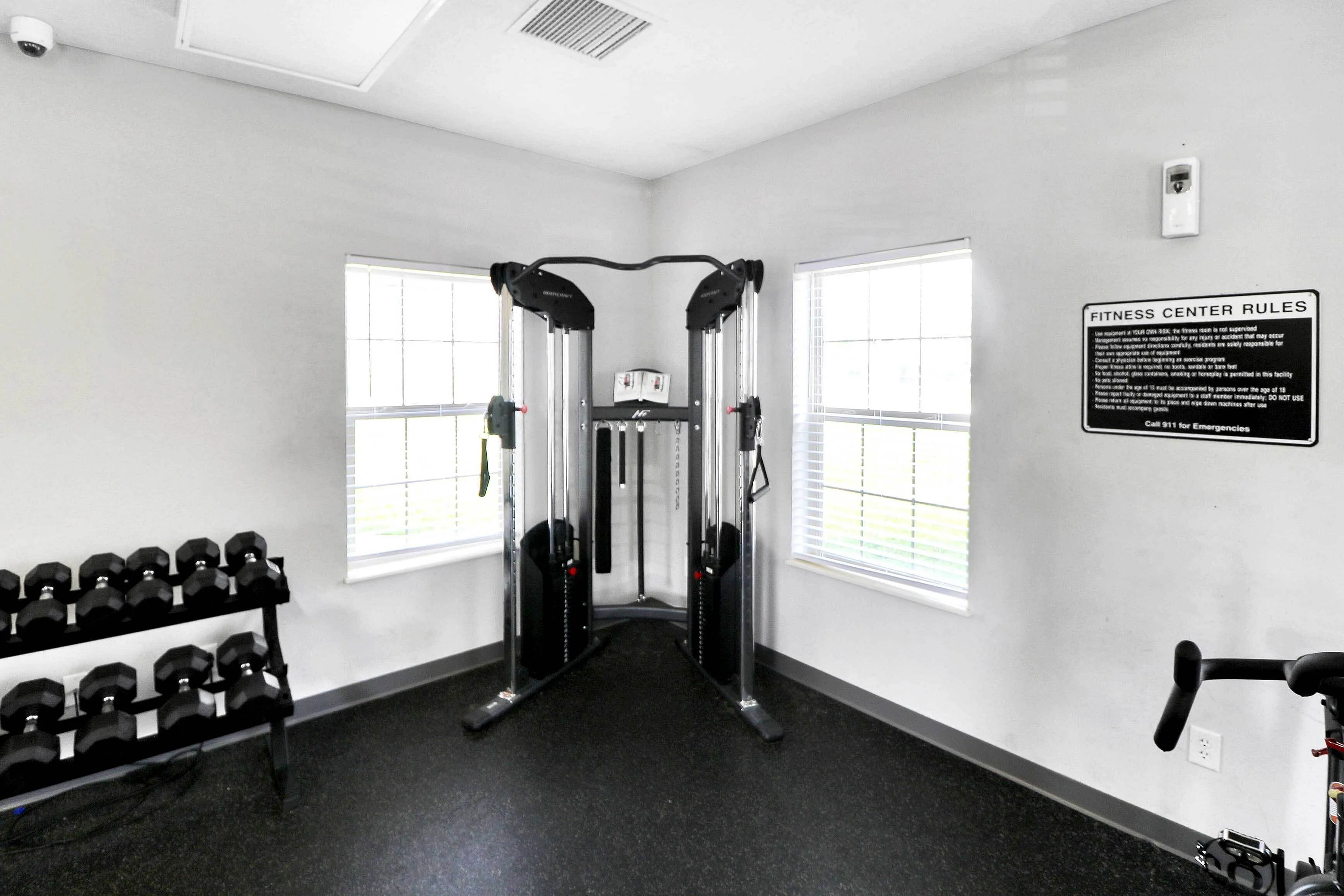 Brightly lit fitness room featuring sleek weight training equipment, modern dual cable machine, and convenient free weights for a comprehensive workout experience.