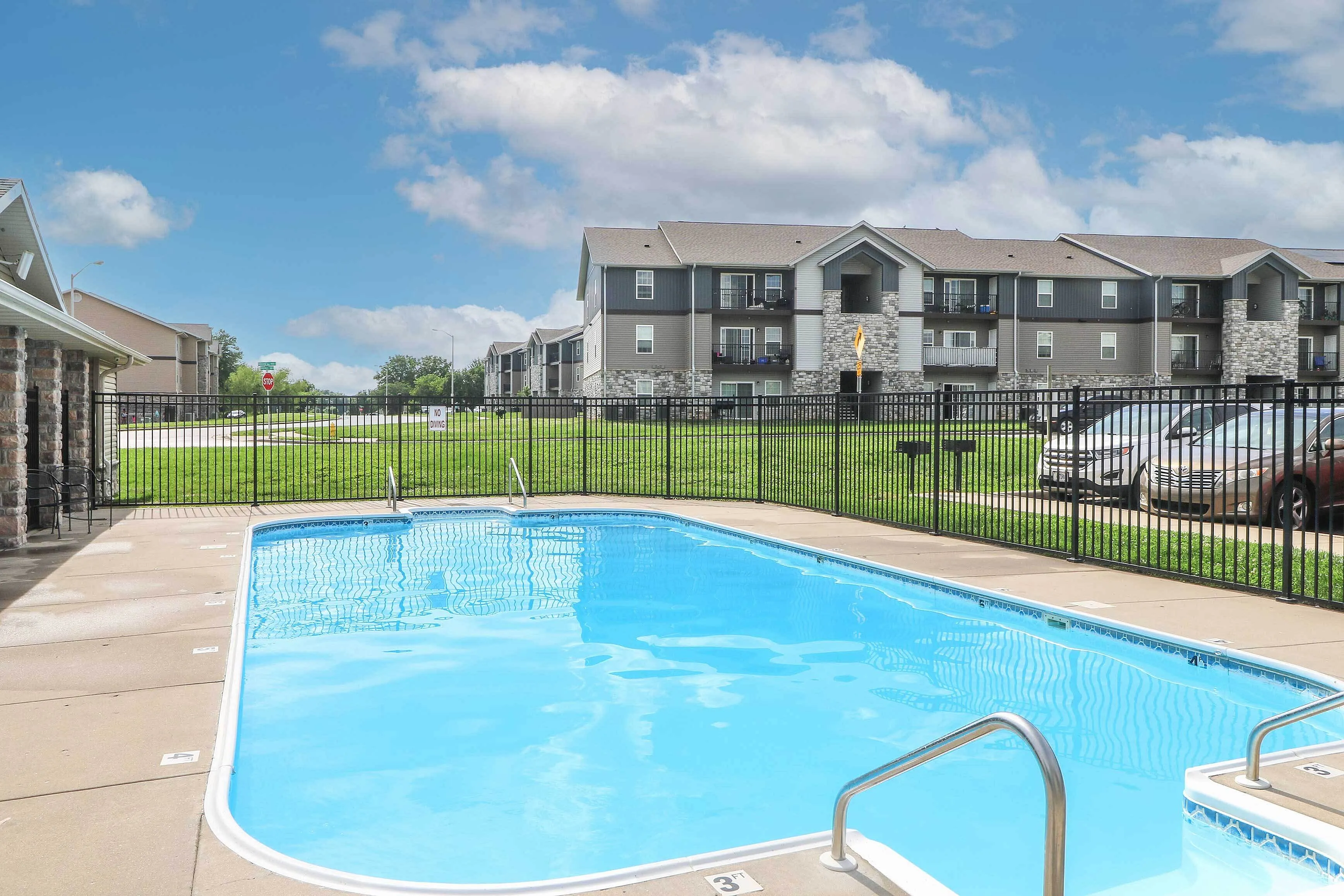 Inviting outdoor swimming pool framed by modern apartment buildings under a vibrant blue sky, perfect for relaxation and leisure.