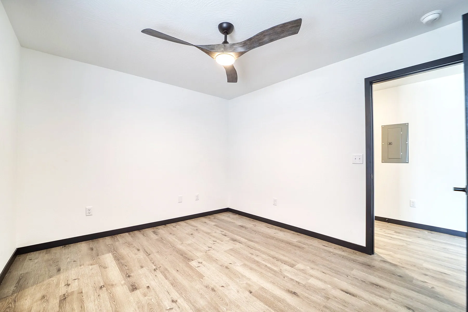 Bright room showcasing modern ceiling fan, sleek wood flooring, and minimalist design.