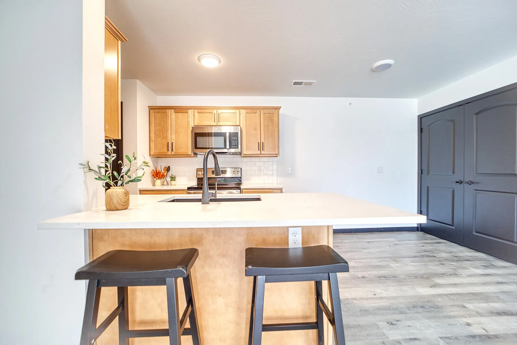 Bright and modern kitchen with sleek countertops, stylish wooden cabinets, and inviting bar stools.