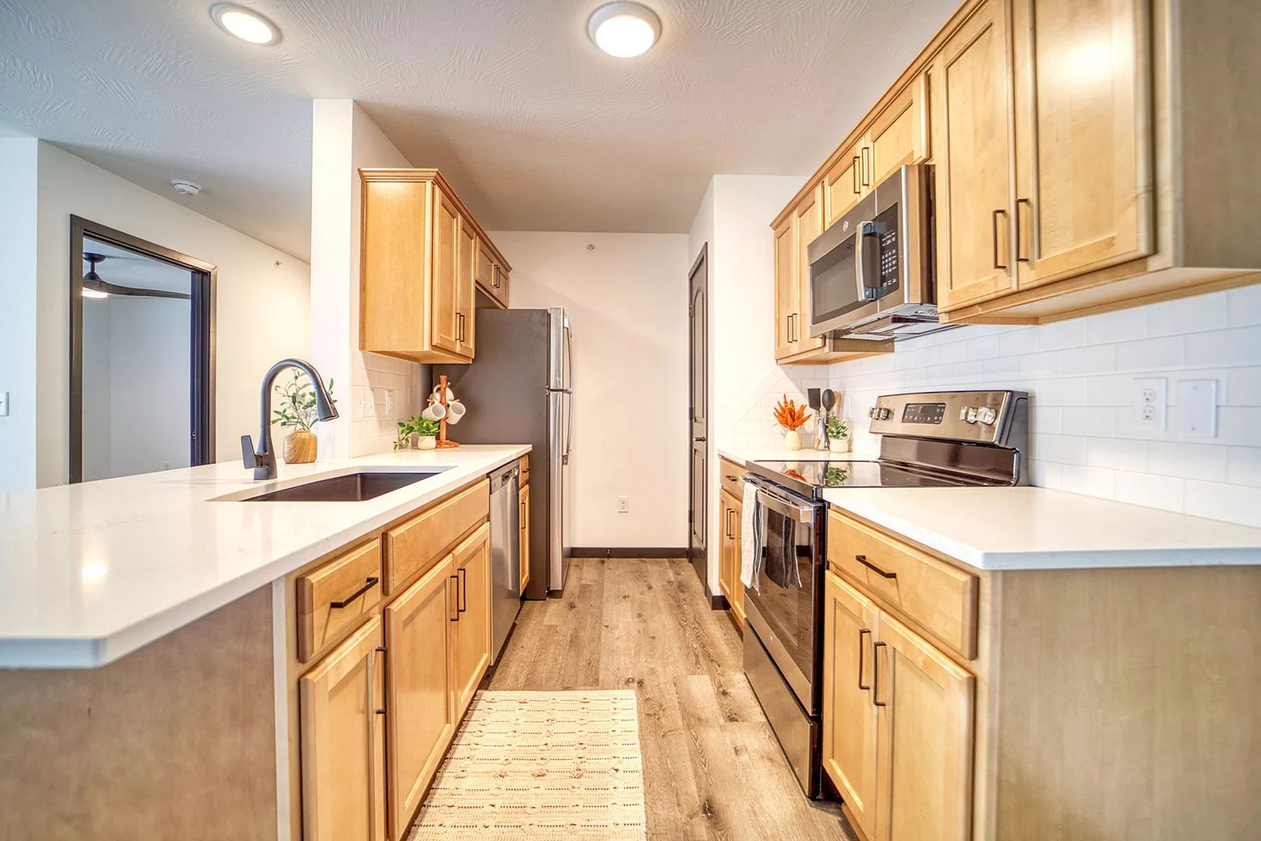 Modern kitchen with warm wood cabinetry, sleek countertops, and stainless steel appliances, perfect for culinary adventures.