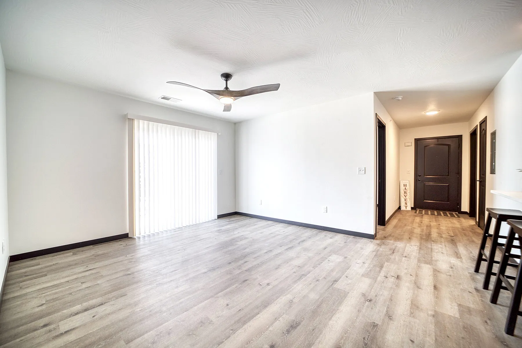Bright and modern living area with elegant wood flooring, large sliding doors, and stylish ceiling fan.