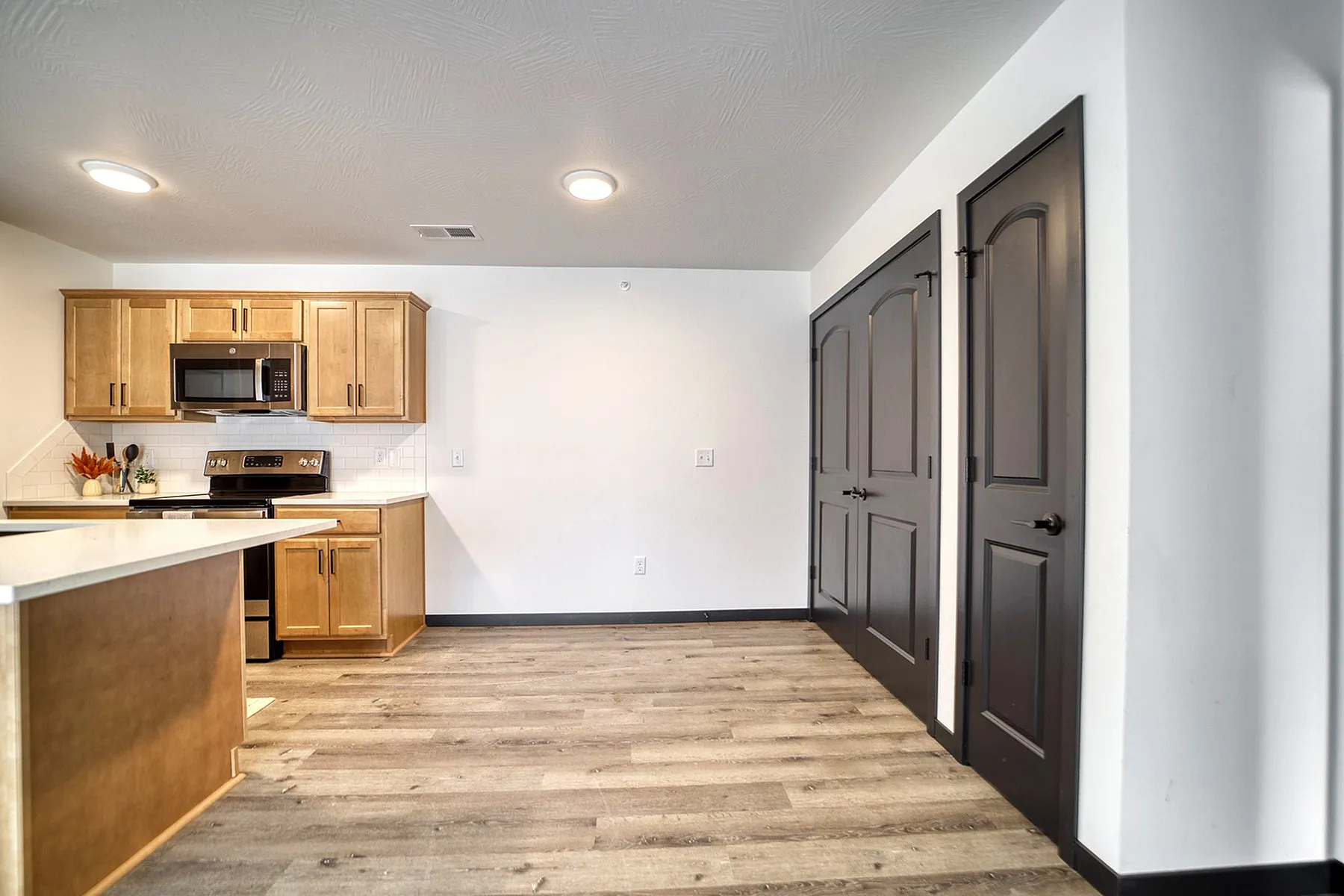Inviting modern kitchen with sleek wood cabinets, stainless steel appliances, and elegant wood flooring.