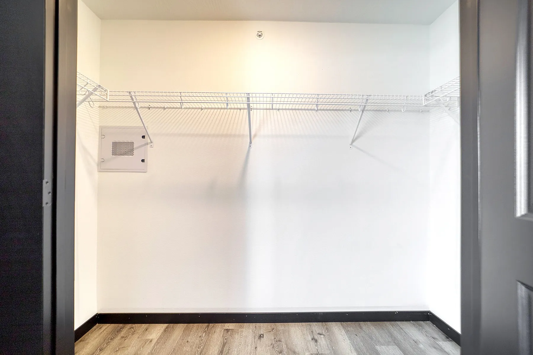 Spacious walk-in closet with sleek shelving and modern flooring, perfect for maximizing storage in a stylish apartment.