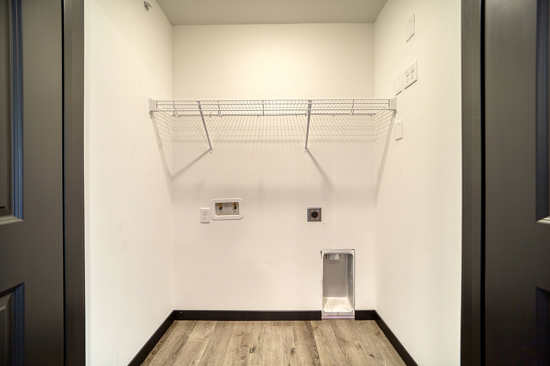 Bright utility room with modern hookups, sleek shelving, and elegant flooring, perfect for efficient laundry tasks.