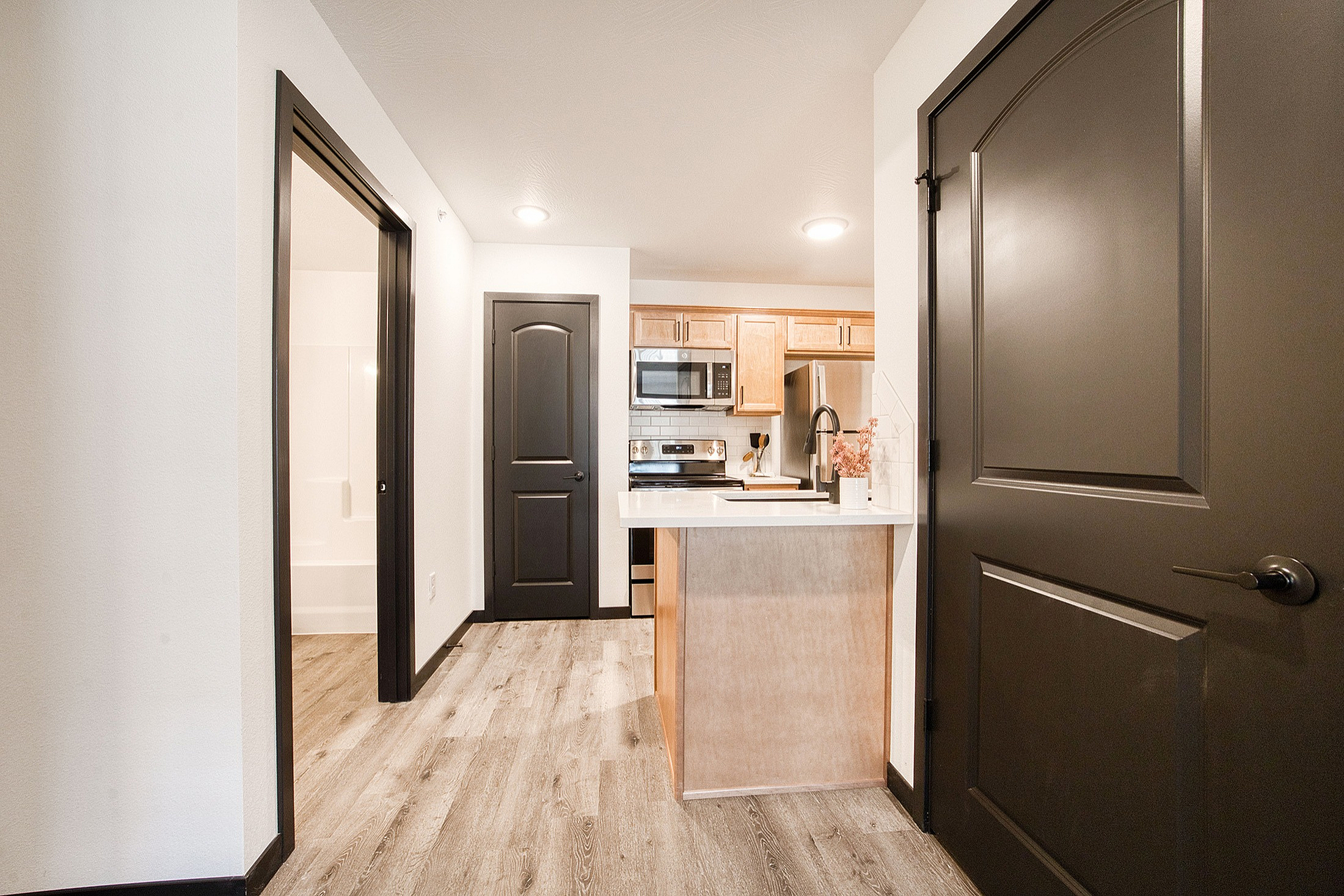 Modern apartment kitchen with sleek cabinetry, stainless steel appliances, and warm wood flooring.