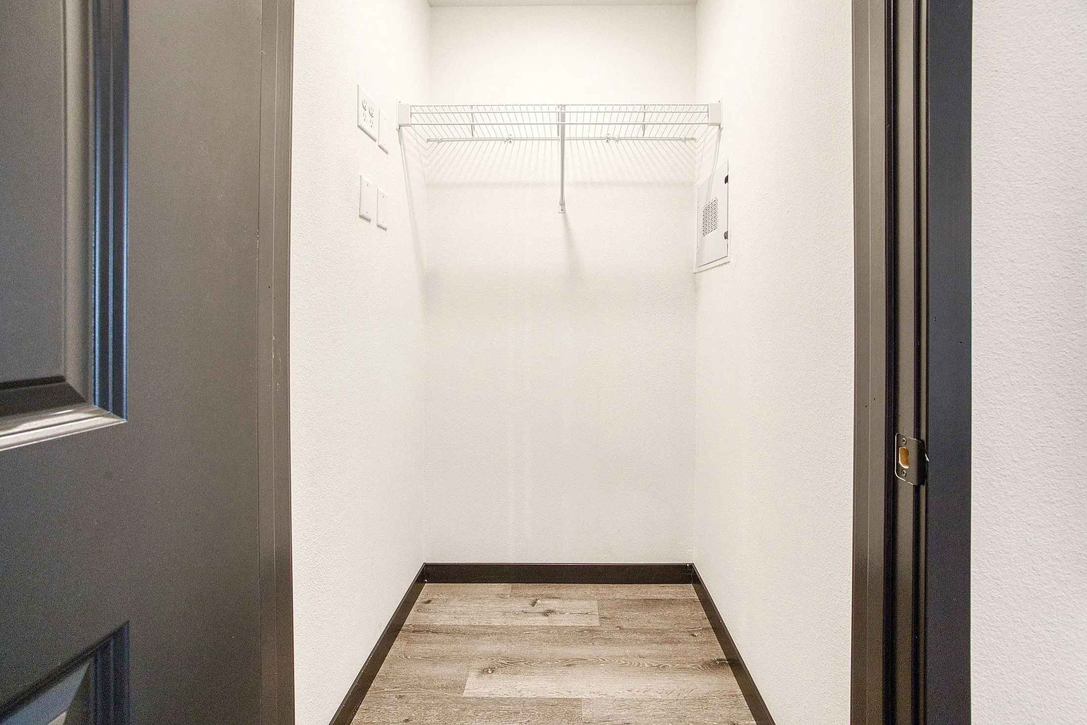 Bright and spacious walk-in closet with modern laminate flooring and sleek shelving, perfect for efficient storage.
