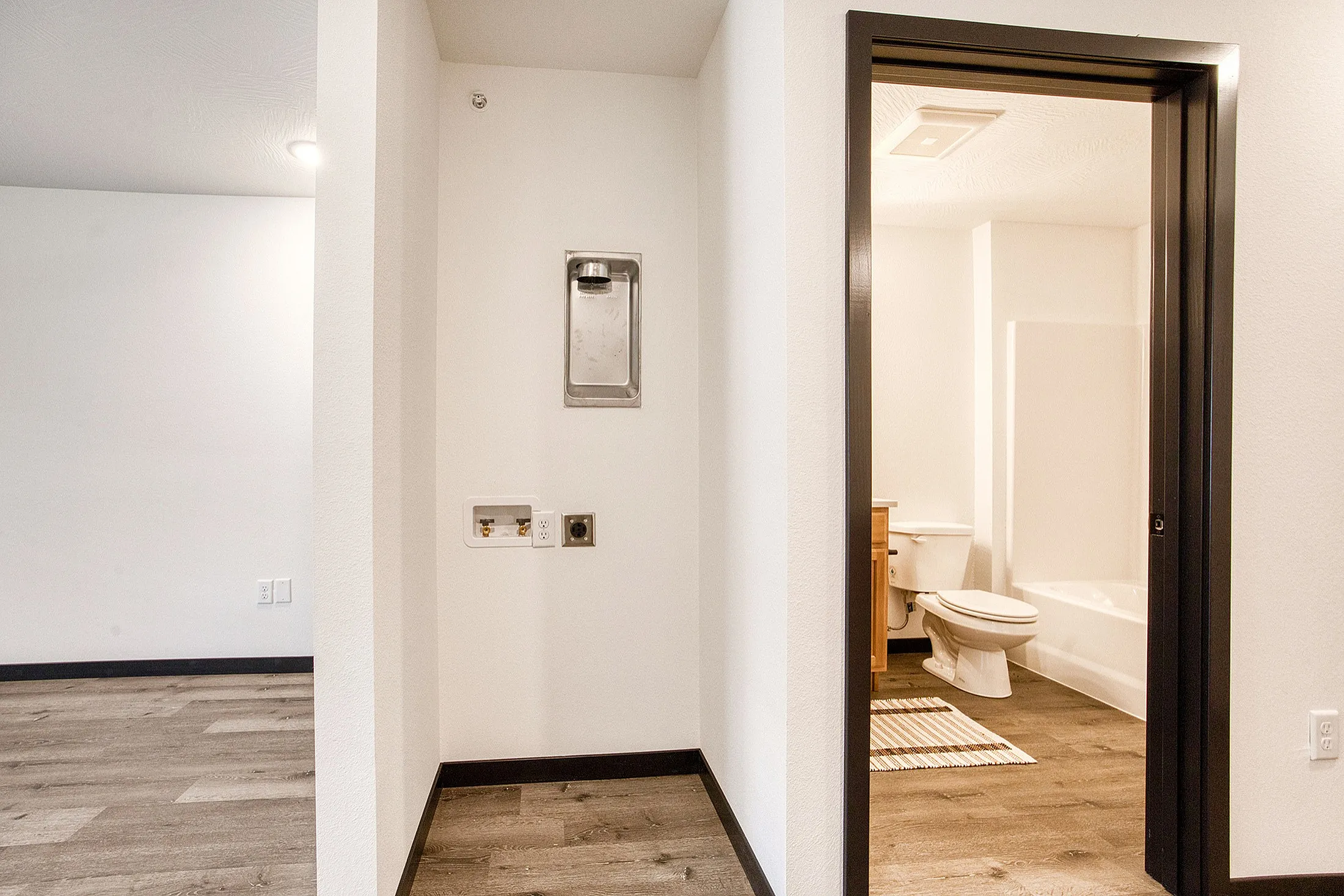 Inviting apartment interior featuring modern bathroom access and sleek hardwood flooring.