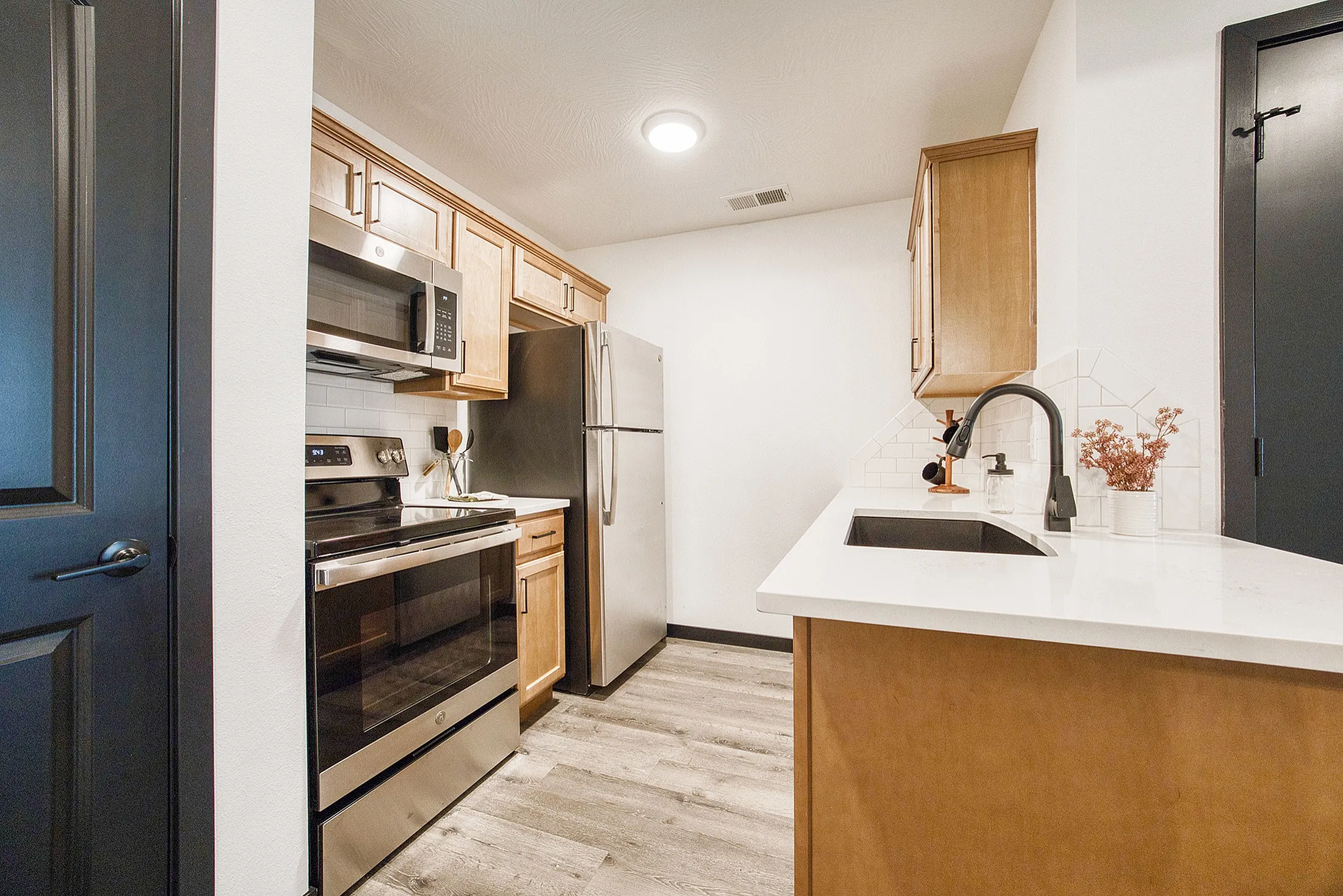 Contemporary kitchen featuring sleek stainless steel appliances, elegant wooden cabinetry, and a stylish white countertop with modern fixtures.