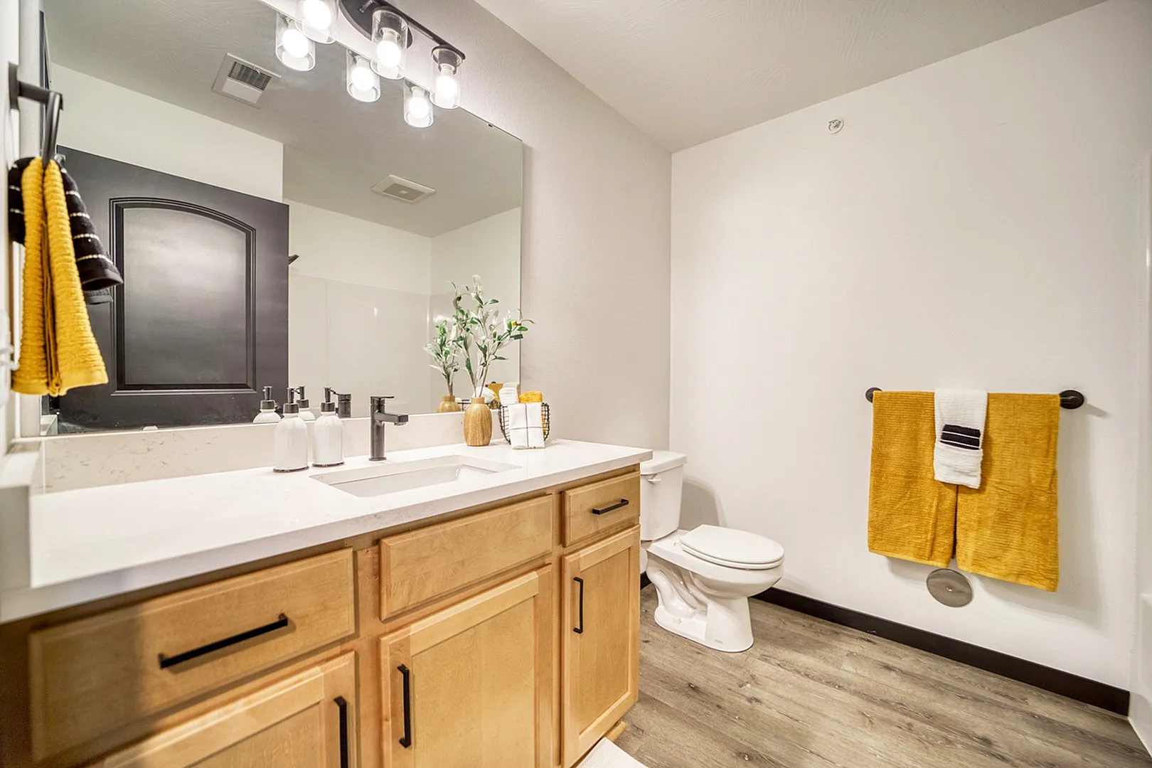 Elegant bathroom featuring modern wooden cabinetry, bright lighting, and stylish yellow accents.