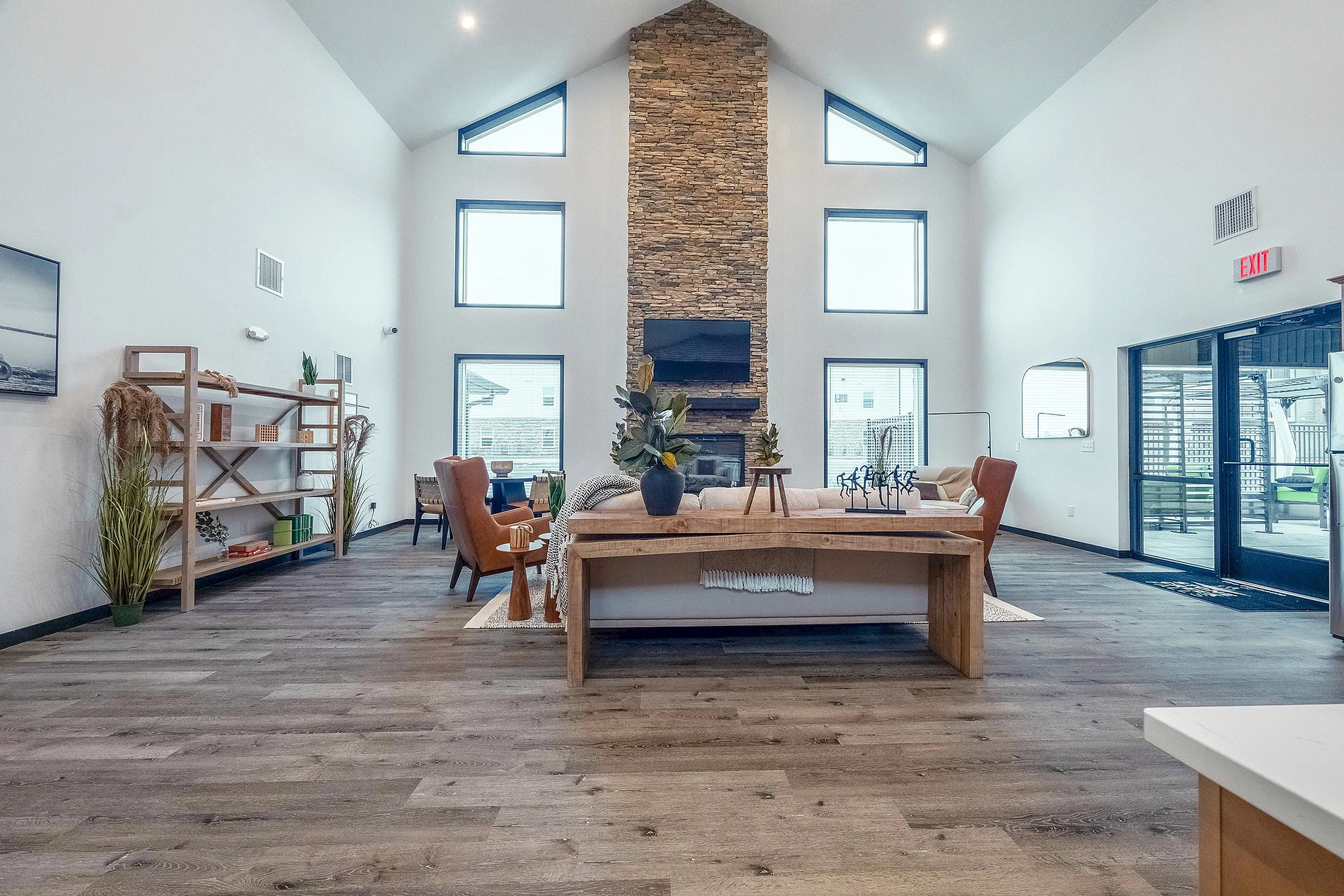 Elegant living room with high ceilings, large windows, and a central stone fireplace. Features stylish furnishings and natural light.