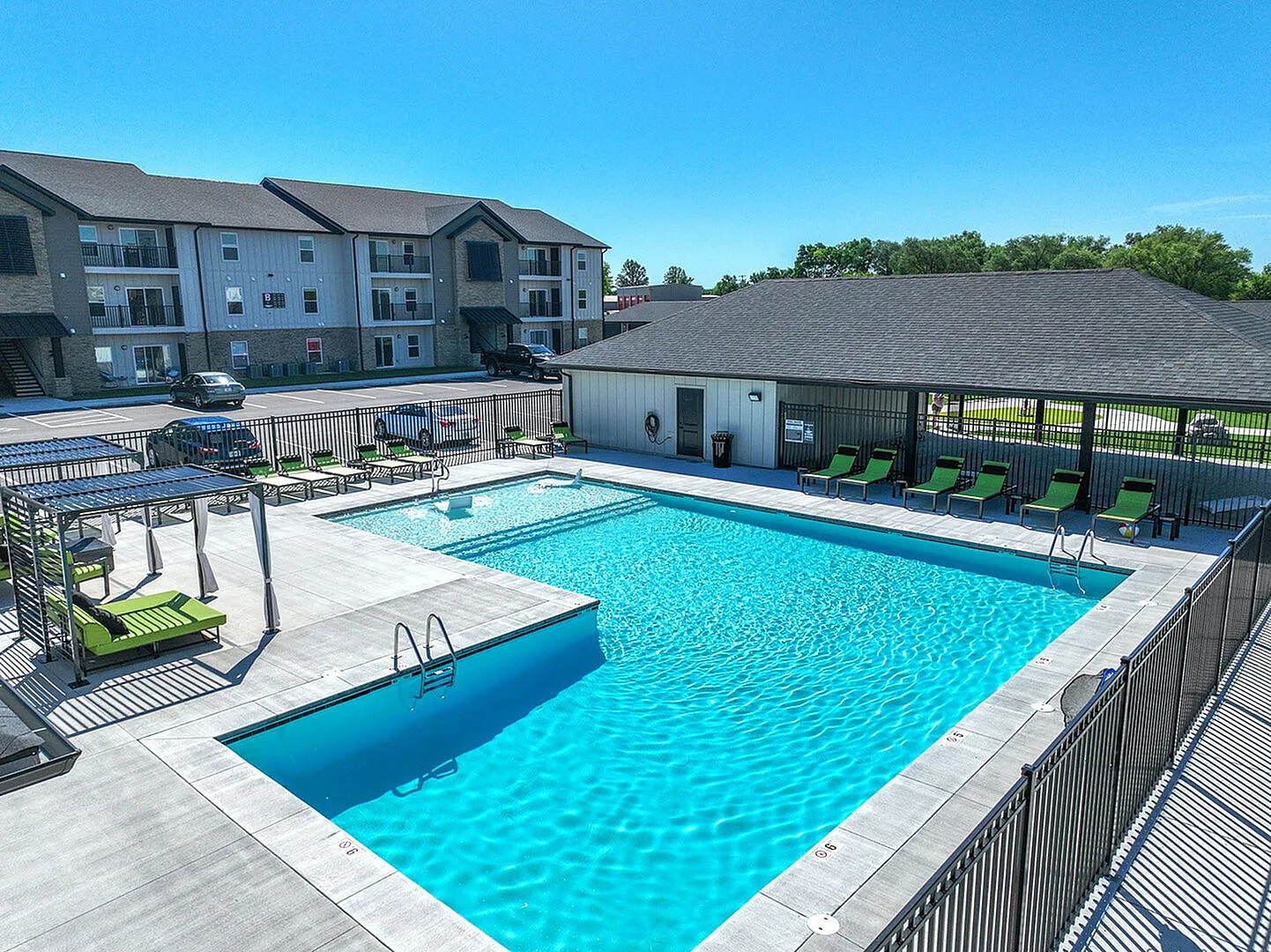 Inviting apartment complex with a sparkling swimming pool, surrounded by cozy lounge chairs and a spacious deck, perfect for relaxation and leisure.