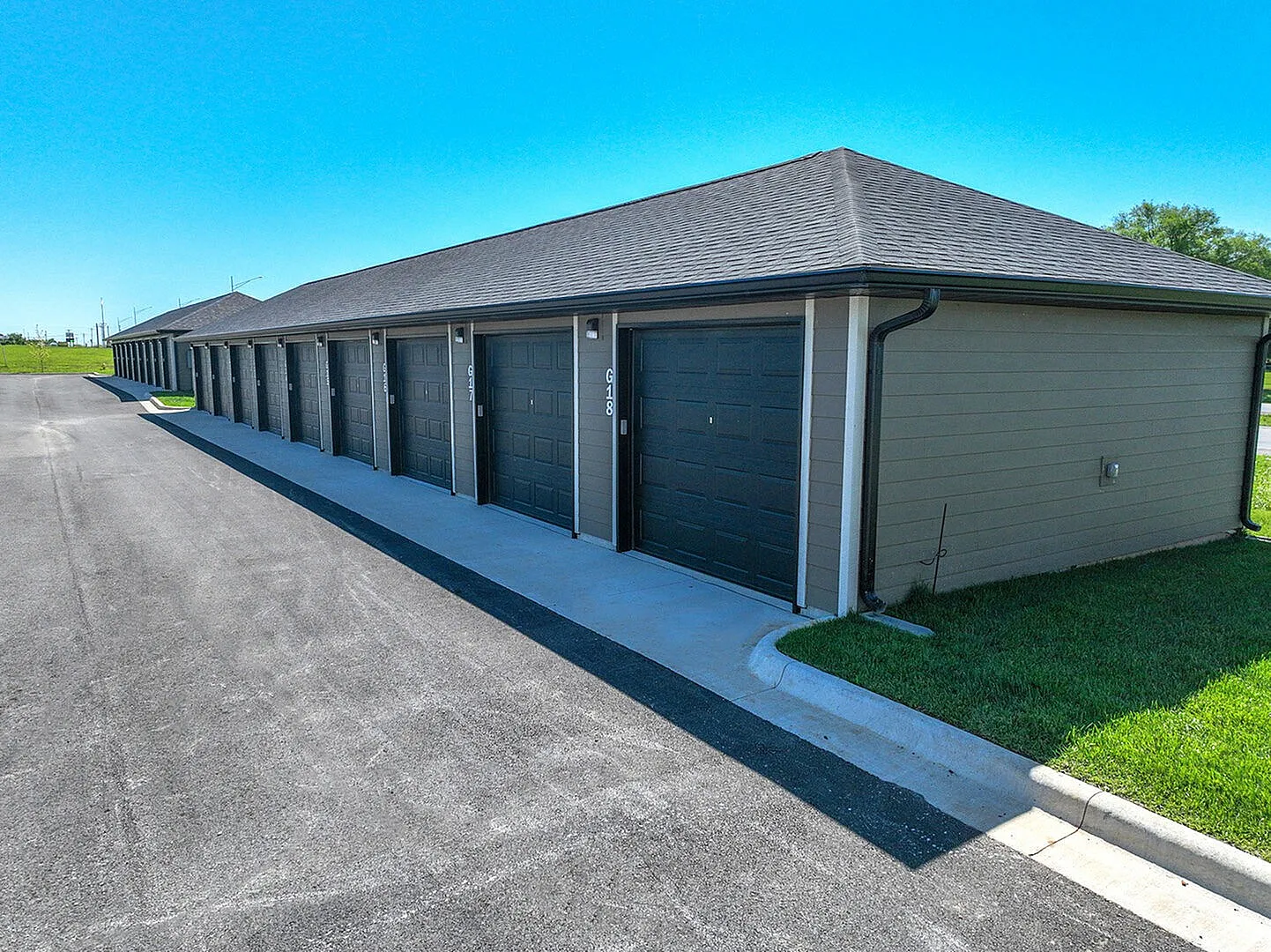 Modern storage units with sleek doors in a well-maintained facility surrounded by lush green grass.