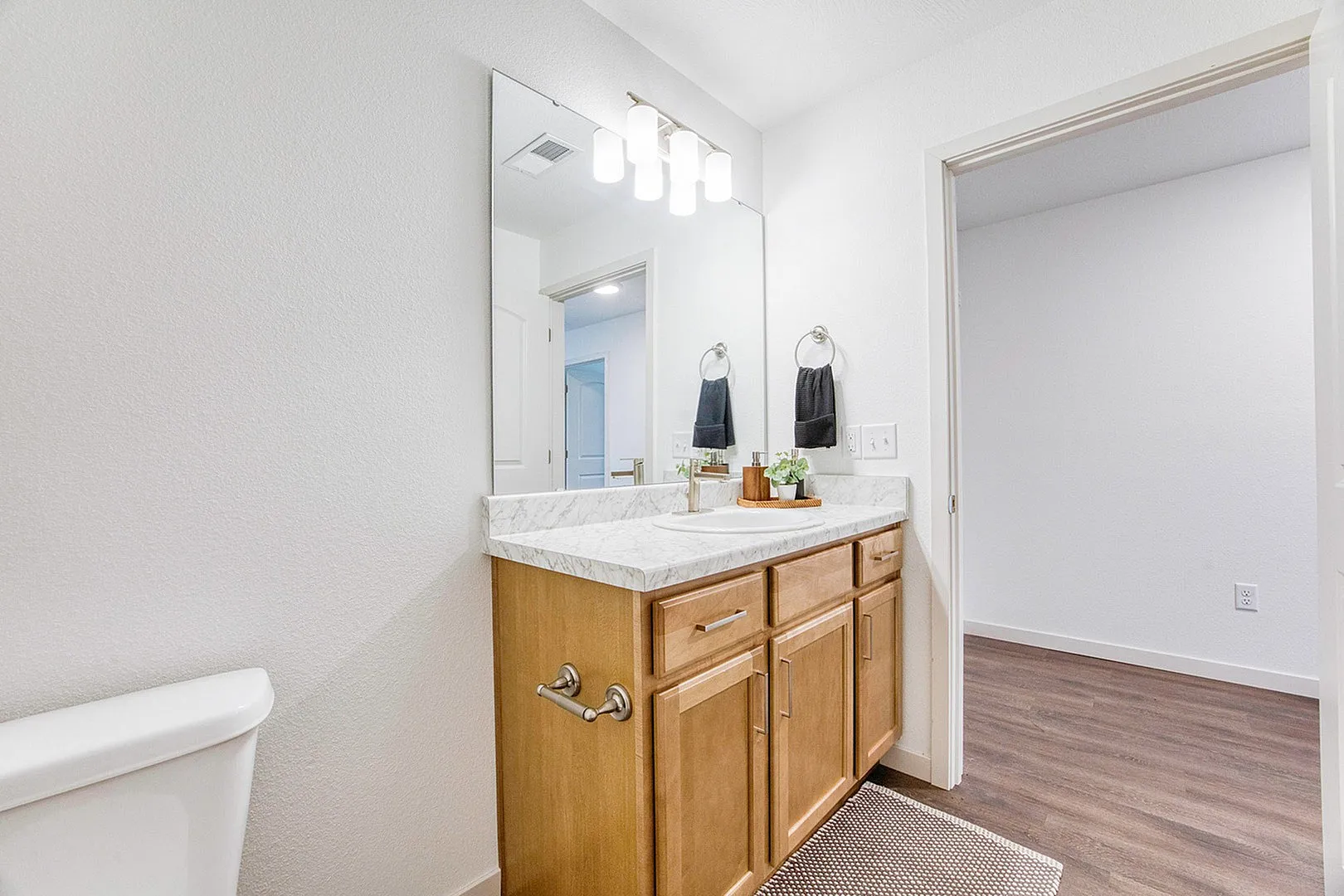 Elegant bathroom with modern marble countertop and stylish wooden cabinetry, accented by sophisticated lighting and chic decor.