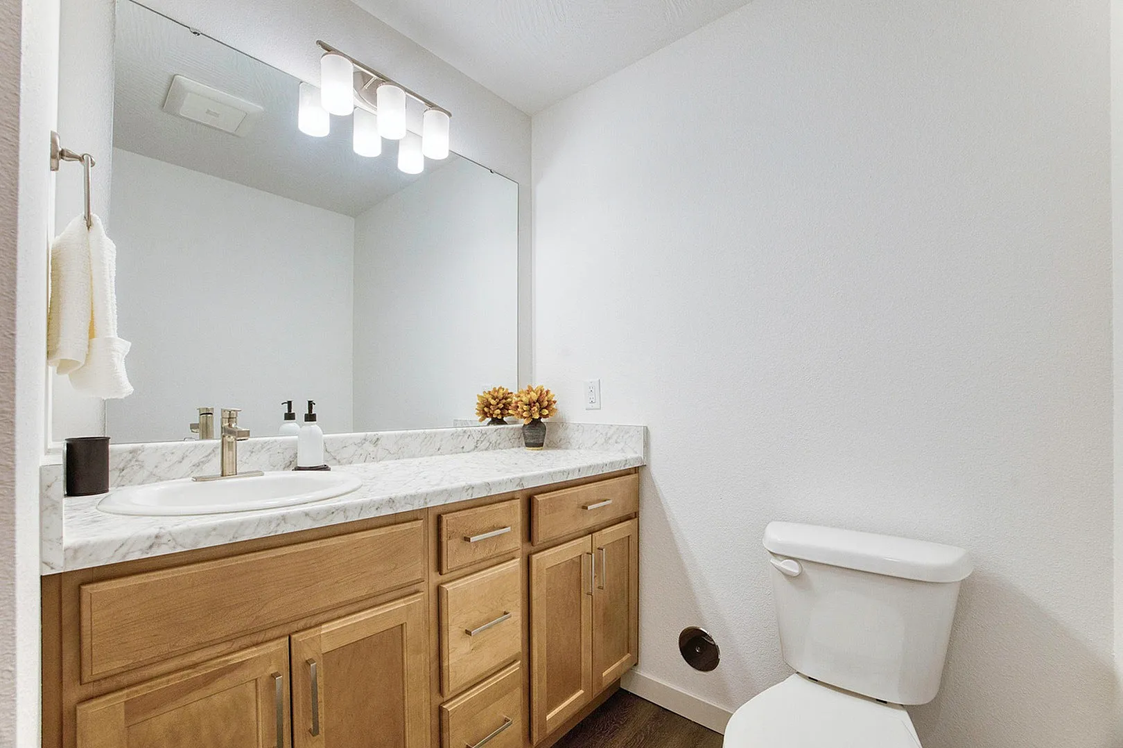 Modern bathroom featuring elegant marble countertops, sleek wooden cabinetry, and a contemporary light fixture.