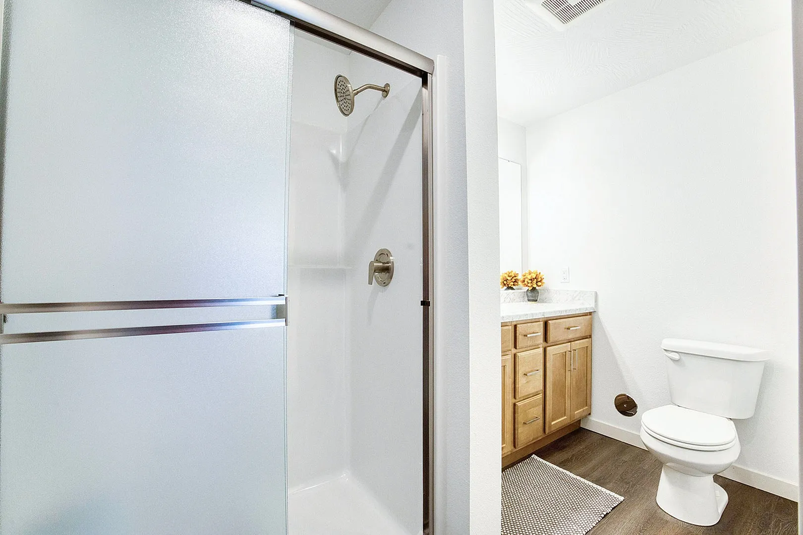 Bright, modern bathroom featuring a sleek shower, elegant vanity, and pristine toilet with high-quality finishes.