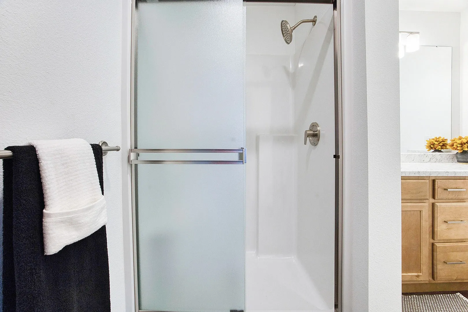 Modern bathroom with a sleek glass shower door, elegant chrome fixtures, and a cozy vanity with natural wood accents.