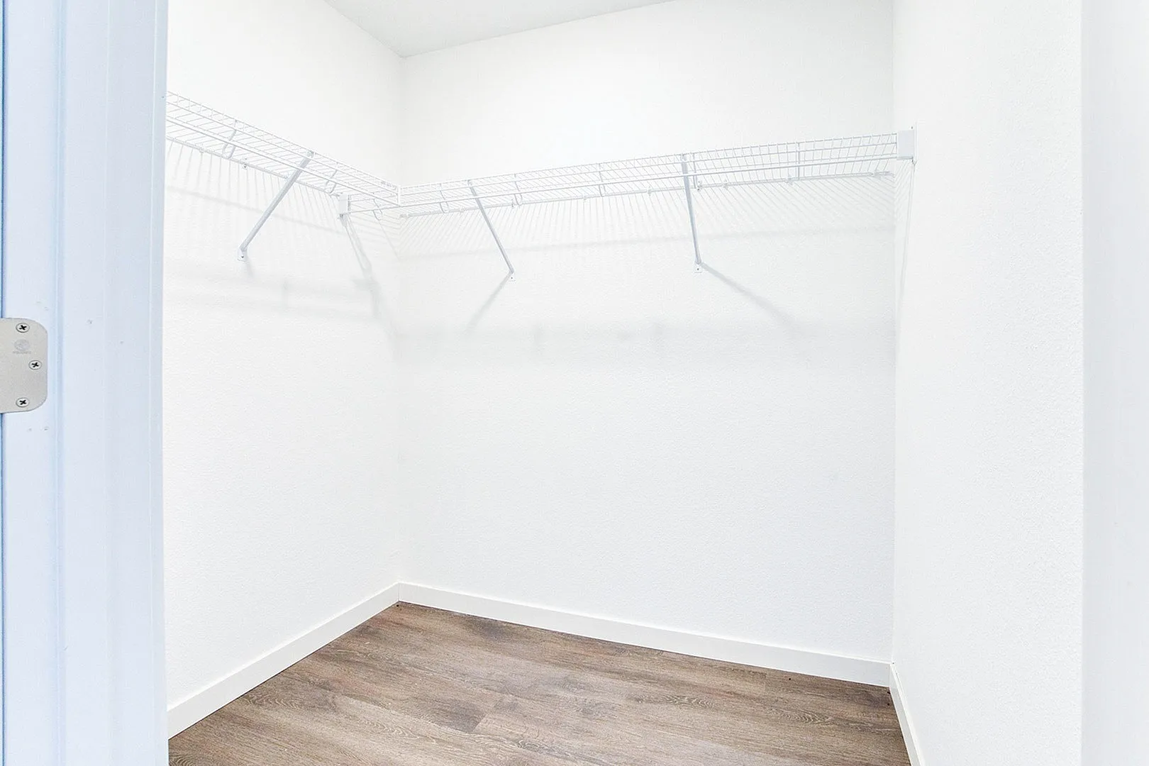 Spacious walk-in closet with modern wire shelving and elegant hardwood floors, perfect for organized storage.