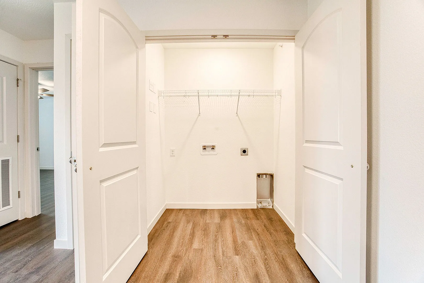 Bright and inviting laundry area with double doors, featuring elegant wood flooring and ample storage space.