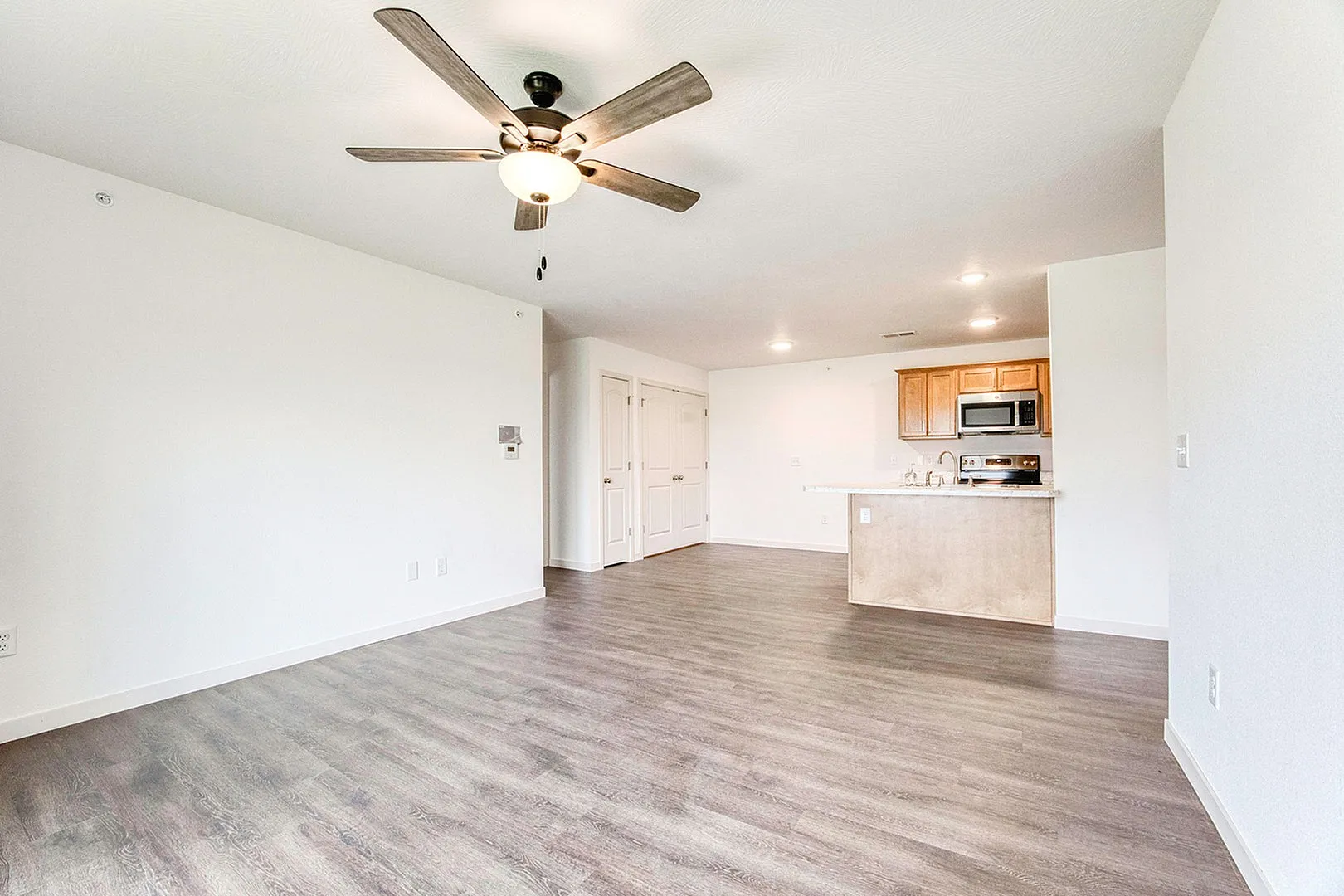 Spacious open-concept living area with modern kitchen featuring sleek wooden cabinetry and stainless steel appliances.