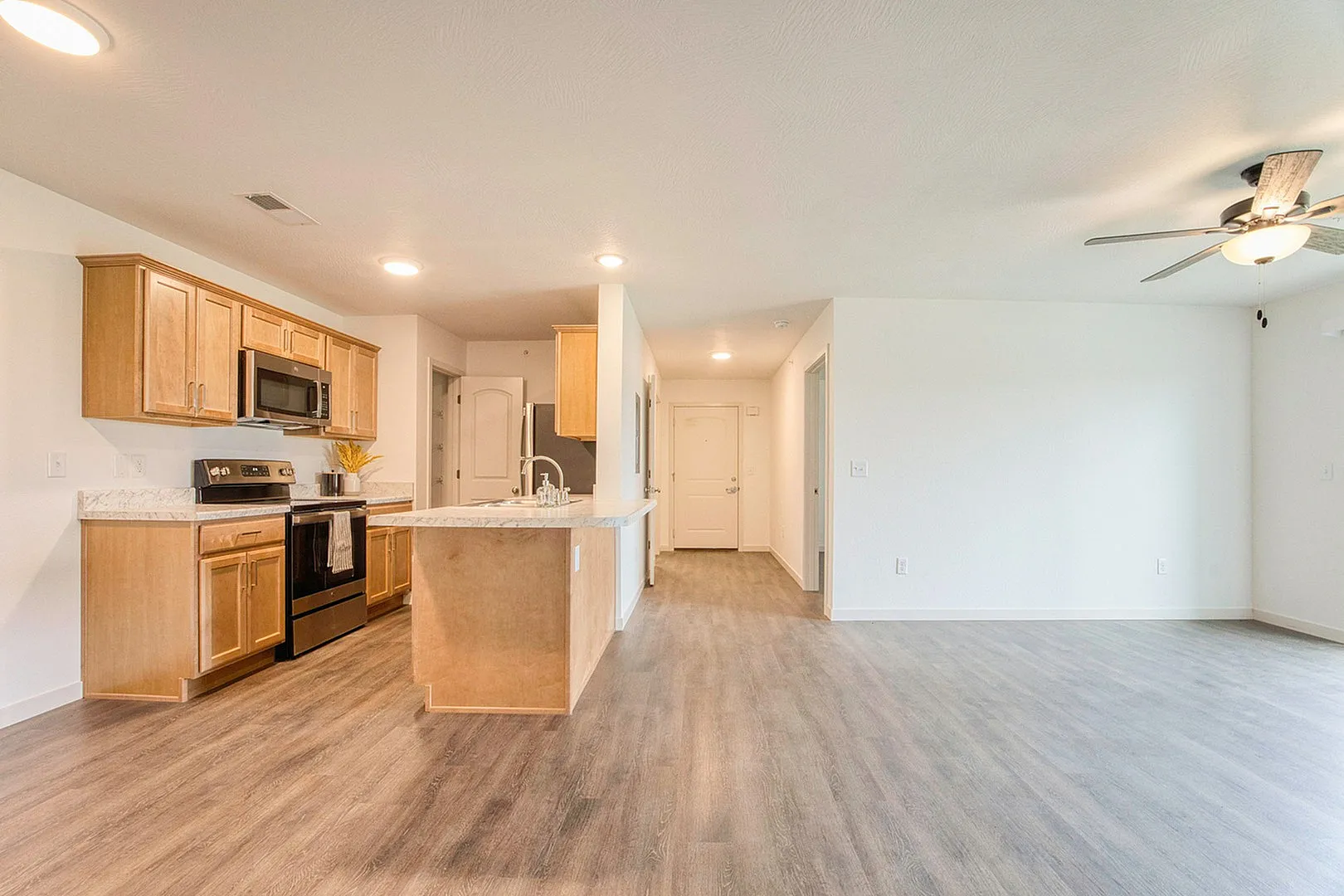 Inviting open-plan kitchen and living room featuring modern wood cabinetry, sleek appliances, and elegant flooring.