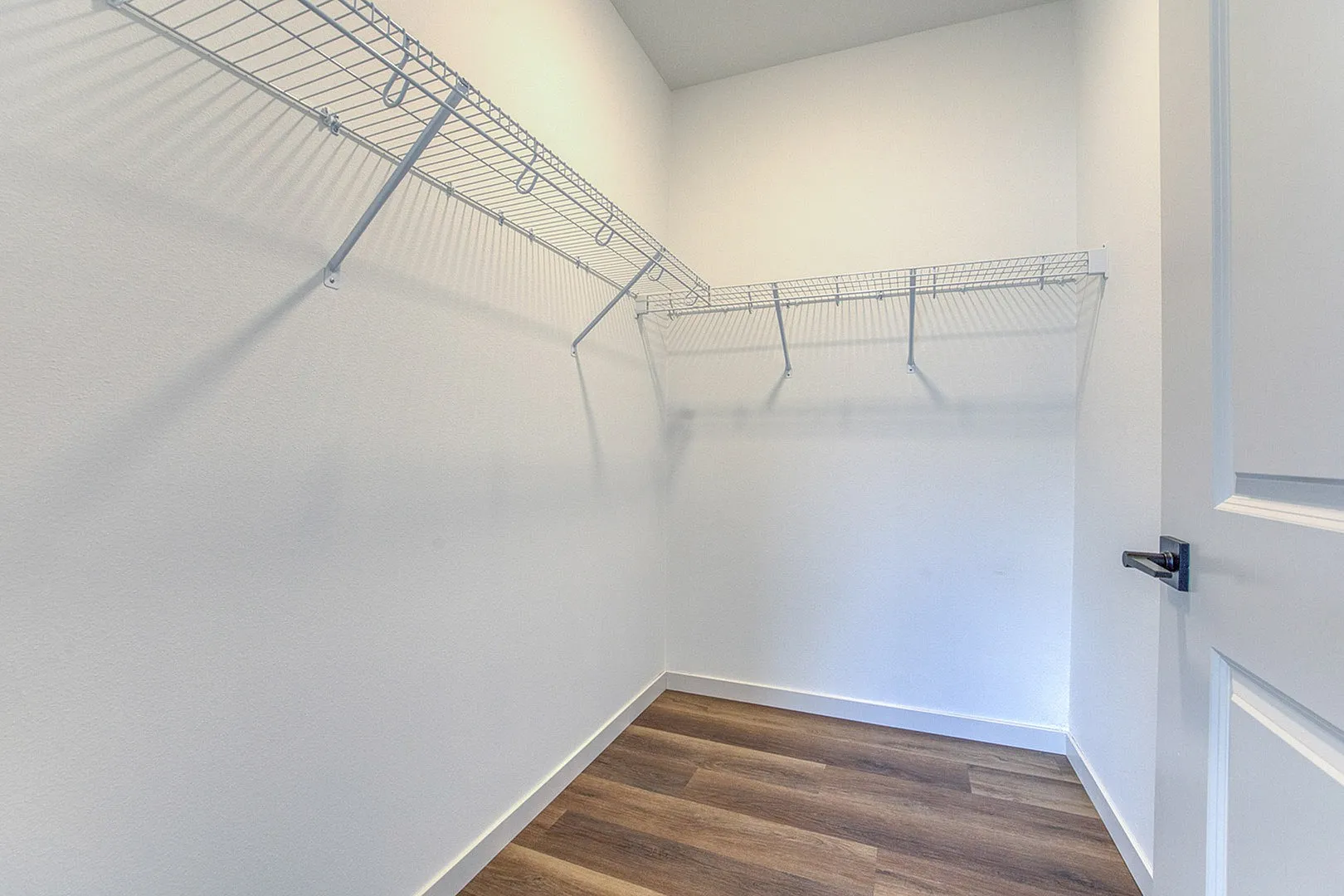 Spacious walk-in closet with modern shelving and elegant hardwood flooring.