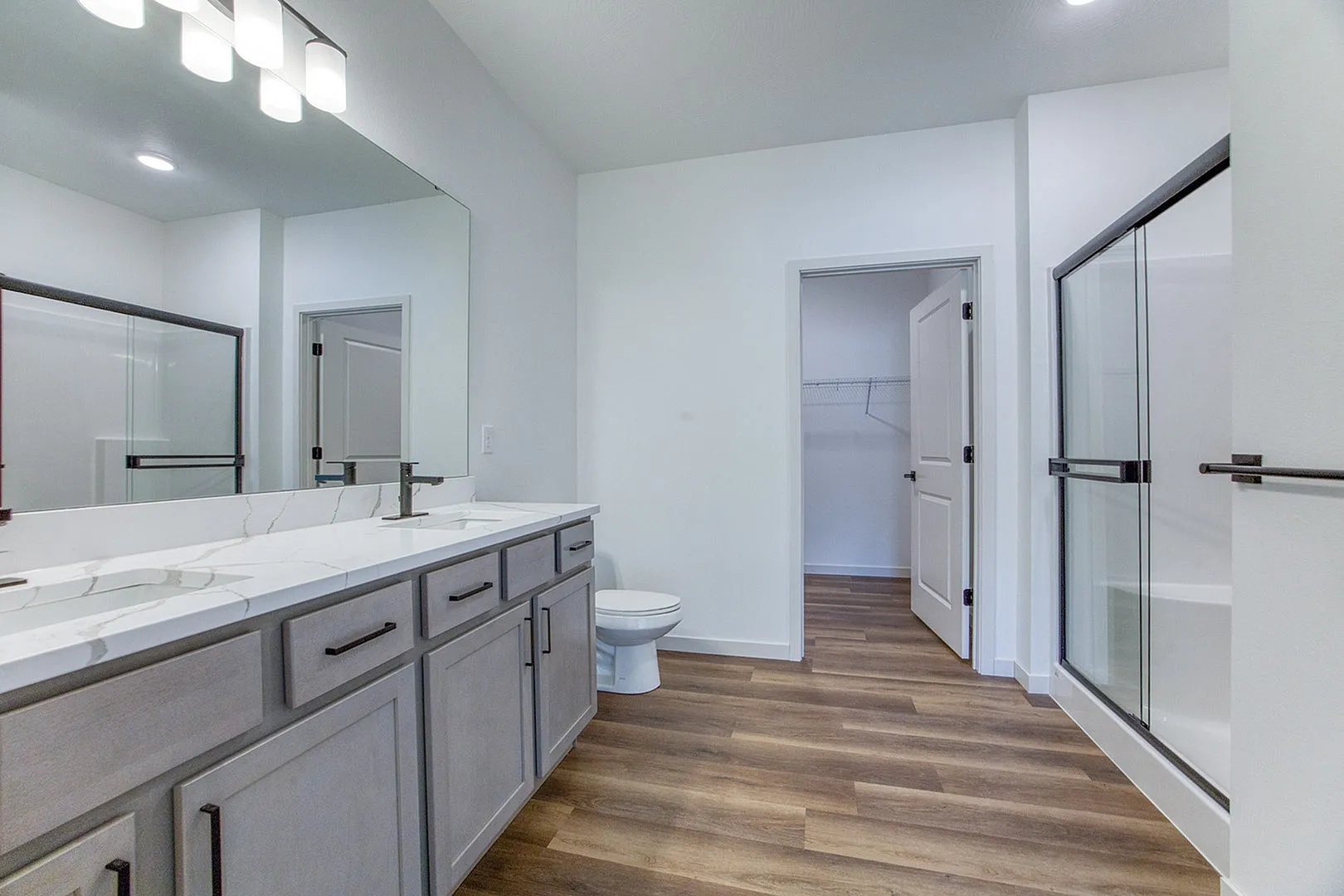 Modern bathroom with elegant marble countertop, sleek double sink vanity, and spacious walk-in shower.